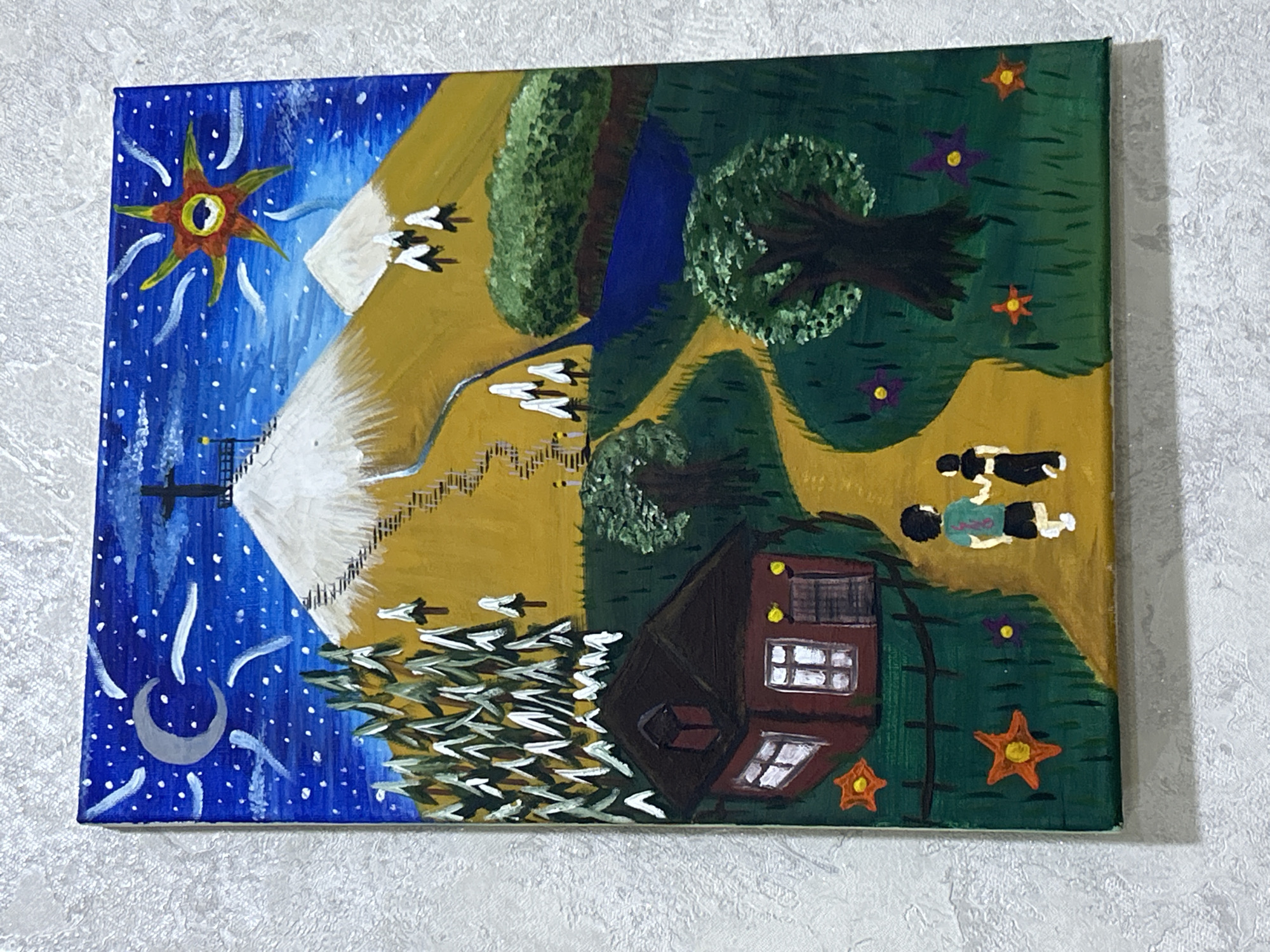 This is a painting of a whimsical landscape. A path winds through green grass dotted with star-shaped orange and purple flowers. On the left, a small, dark red house with white-paned windows and a dark roof sits behind a black fence. Two children, one in a teal shirt and shorts, the other in a black outfit, walk away from the viewer on the path. To the right of the house, a dark-trunked tree with a full green canopy stands. Further back, a winding blue river flows past a large green bush. The path continues towards a large, golden mountain with a snowy peak topped by a cross. A staircase ascends the side of the mountain. In the blue night sky, a crescent moon with a subtle halo hangs to the left, while a stylized, sun-like object with a red and yellow eye is on the right. The sky is filled with white dots representing stars and wisps of white clouds. Pine trees with white-tipped branches are scattered across the landscape, with denser clusters near the house and on the mountain. The painting is on canvas and appears to be a naive or folk art style. The location is not specified within the city of Unknown, Unknown.