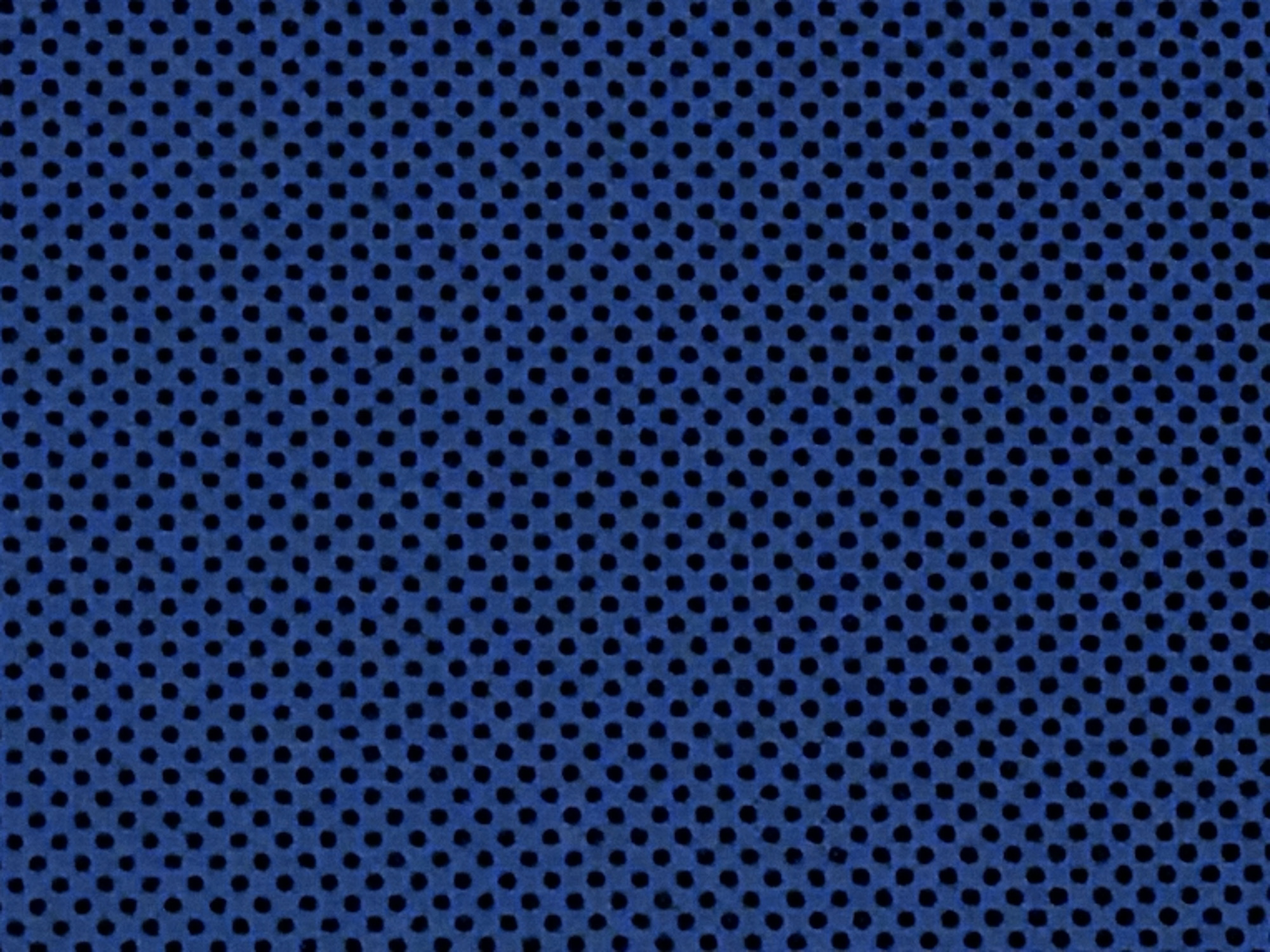 The image shows a close-up of blue fabric with a repeating pattern of small, circular black holes. The holes are arranged in a grid-like formation, creating a mesh-like texture. There is no indication of the location in the city of Noviy, Russia, or any people, subjects, objects, actions, interactions, or environment other than the fabric itself.