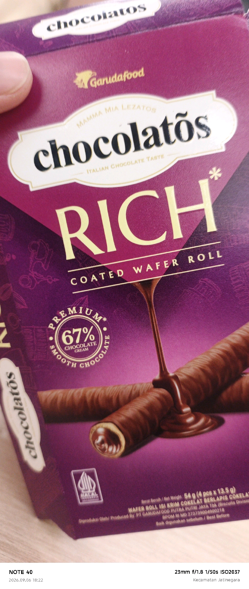 A box of "Rich Chocolateatos" wafer rolls is partially shown. The box is primarily purple and features the "GarudaFood" logo. The product name "Rich" is prominently displayed in large, yellow lettering, with "Coated Wafer Roll" below it. A circular emblem indicates "Premium" with "67% Chocolate Cream" and "Smooth Chocolate" text. The image also shows two chocolate wafer rolls with chocolate sauce drizzled over them. The bottom of the box has text in Indonesian including "Berat Bersih / Net Weight: 54 g (4 pcs x 13.5 g)" and "WAFER ROLL ISI KRIM COKELAT BERLAPIS COKELAT". A "HALAL" logo is also visible. The image was taken in Kecamatan Jatinegara, East Jakarta, Indonesia. The timestamp indicates it was taken on 2026.09.06 at 18:22.