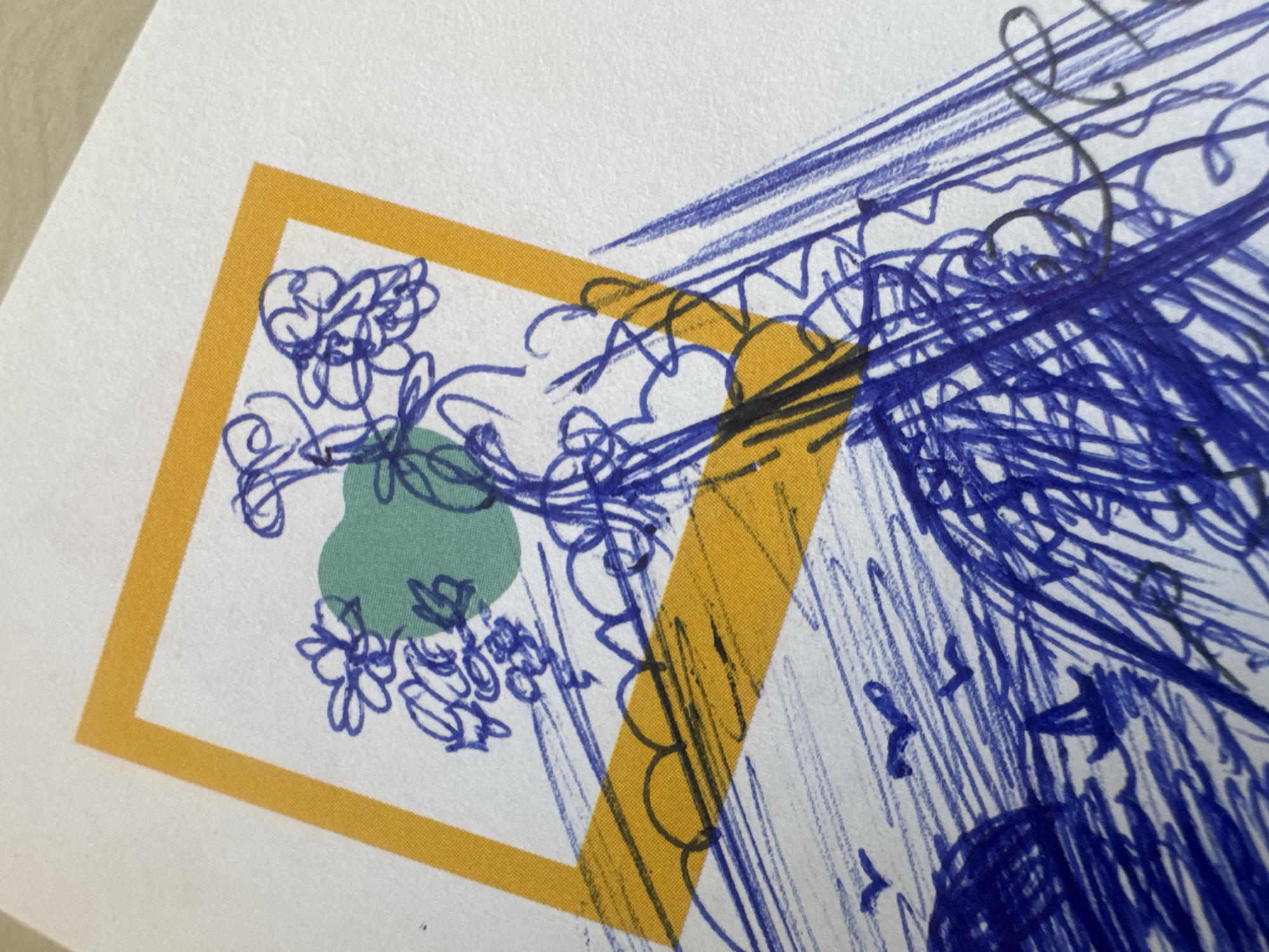 The image shows a section of a drawing on white paper. There is a yellow square outline containing blue scribbled floral patterns and a green blob. A yellow stripe bisects the square. The rest of the paper contains dense scribbles of blue lines.
There is no specific information in the image that suggests a location in Tel-Aviv, Israel, or any other place.