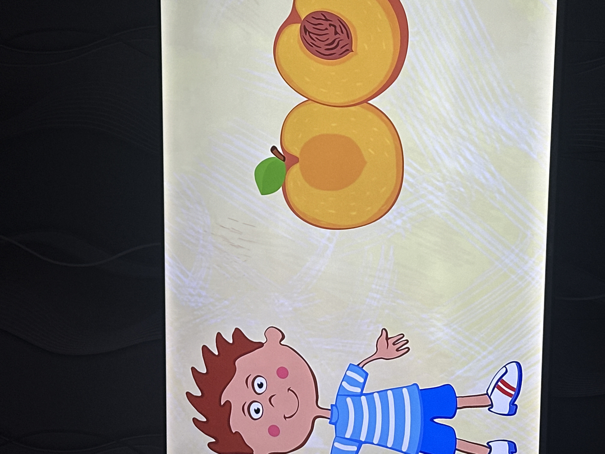 The image shows a cartoon of a boy lying down with two halved peaches stacked above him. The boy has brown hair, a pink face with rosy cheeks, and is wearing a blue and white striped shirt and blue shorts. He has one arm raised and is wearing white sneakers with red stripes. The peaches are golden yellow with a brown seed visible in the top half, and a green leaf attached to the bottom half. The background is light yellow with a subtle texture.