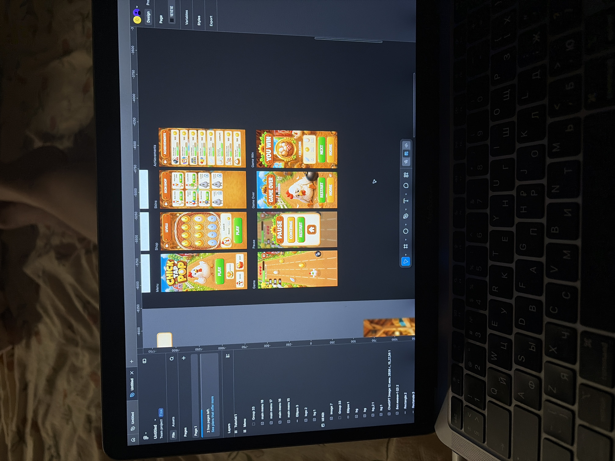 The image shows a laptop screen displaying a game development or design interface. The screen is divided into several panels, including a project overview on the left with tabs for "File," "Assets," "Pages," and "Layers." The main area of the screen shows multiple artboards, each representing a different screen or element of a game. These artboards include a "Menu" screen with a "CHICK TAP POP" title, a "Shop" screen with various items and currency, a "Levels" screen showing numbered circles, an "Achievements" screen, a "Pause" screen, a "Game Over" screen with a chicken and coins, and a "Game Win" screen also displaying coins. There are also controls and menus visible, suggesting an interactive design tool. The laptop itself is positioned on a person's lap, indicated by the visible keyboard with both Latin and Cyrillic characters. The background is blurred and appears to be an indoor environment, possibly a home or cafe. There is no visible information or context within the image to suggest a specific location in Hà Nội, Vietnam.