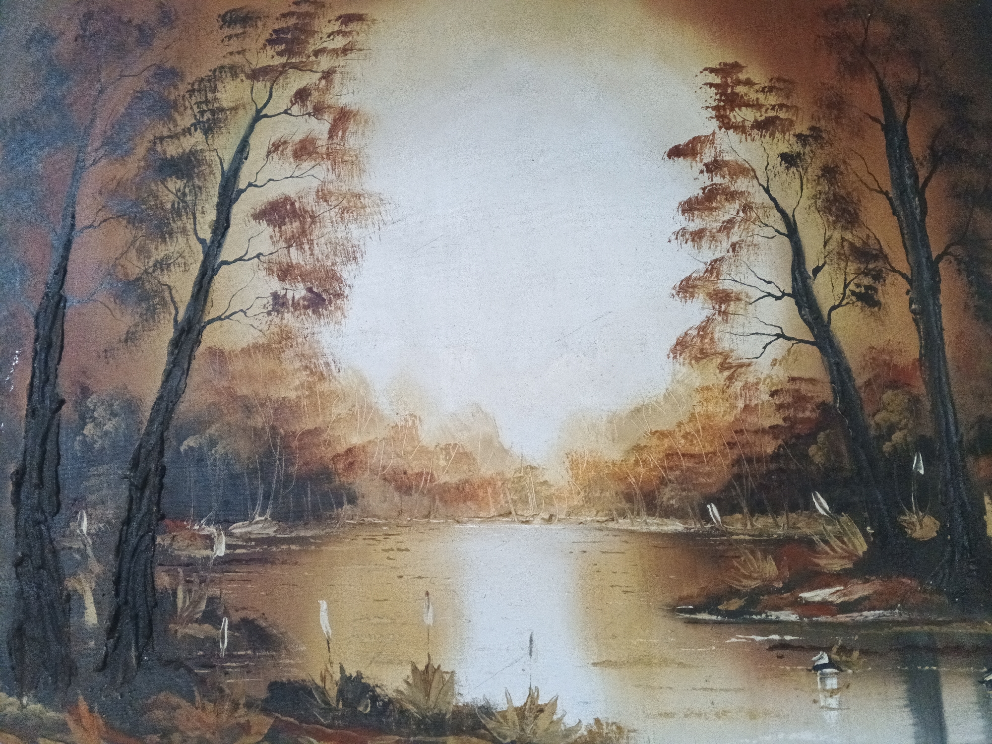 The image is a painting of a landscape featuring a body of water surrounded by trees. The scene is bathed in warm, autumnal colors, with shades of brown, orange, and yellow dominating the palette. The sky is obscured by a bright, diffused light source, creating a sense of openness and depth. The trees are mostly bare, with some foliage still clinging to their branches. The water is calm, reflecting the colors of the sky and trees. There are no people visible in the scene. The composition is symmetrical, with the trees framing the body of water on either side. There are no specific details in the image to suggest the location is Caracas, Venezuela.