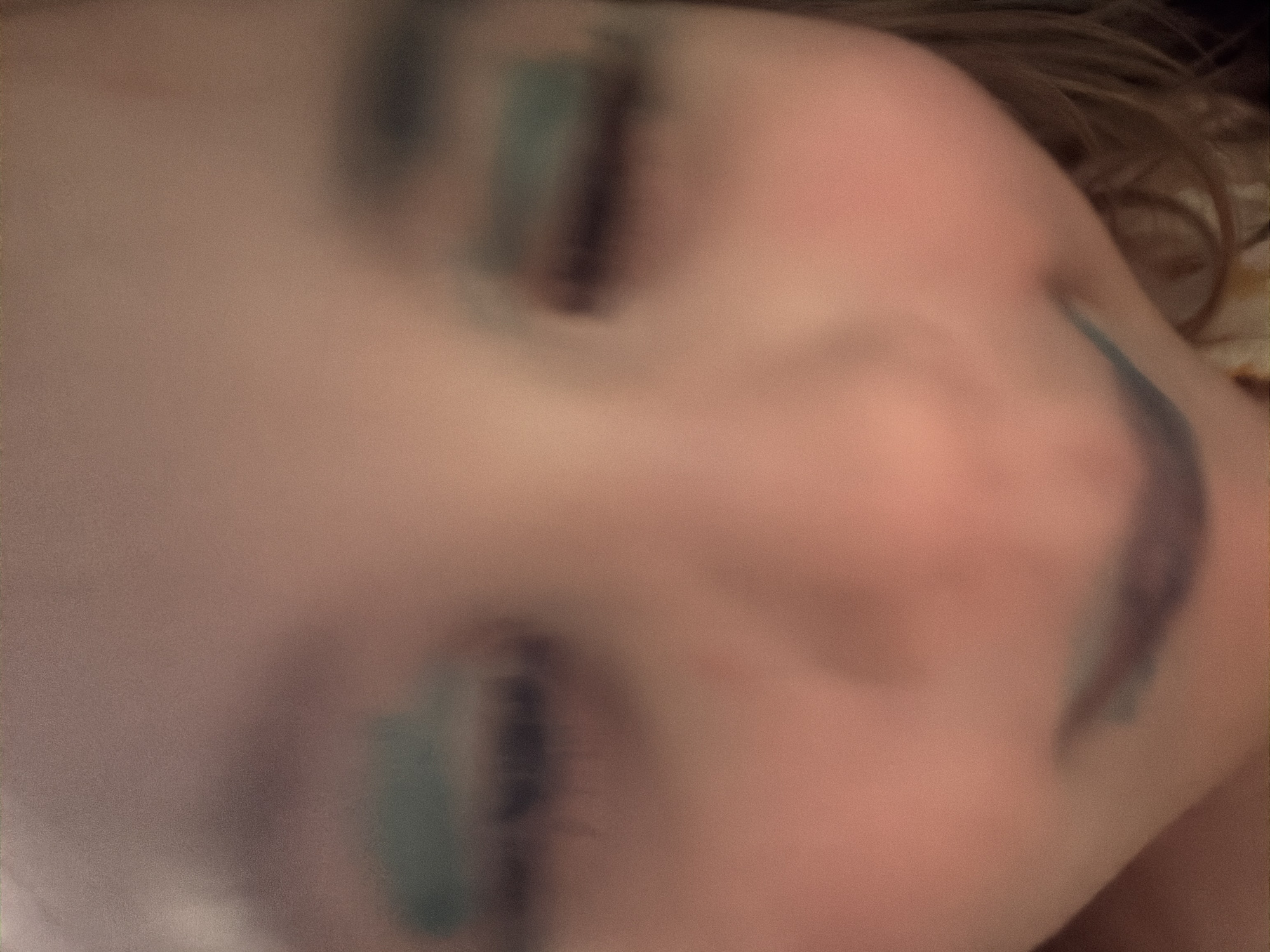 The image shows a close-up, out-of-focus view of a young child's face, with apparent smudges of makeup on their eyelids and lips. The child's eyes are closed, and their mouth is partially open, revealing a dark smudge that appears to be lipstick. The background is indistinct and appears to be an indoor setting. There are no identifiable landmarks or clues within the image to suggest a location in Tambov, Russia, or any specific urban environment.