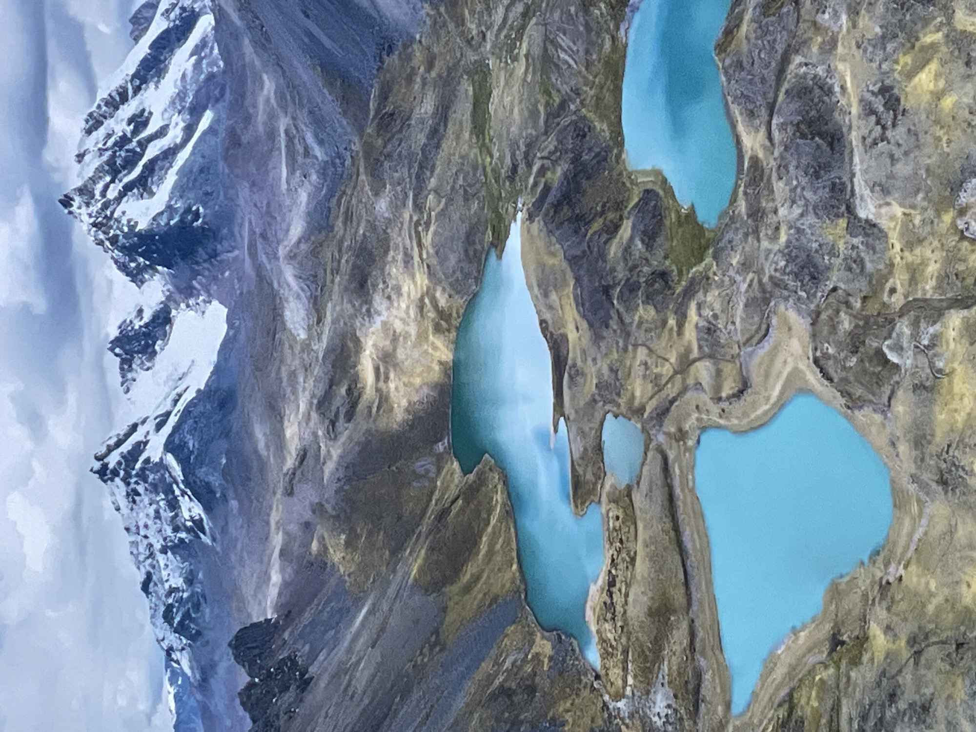 The image displays a breathtaking aerial view of a rugged, high-altitude mountainous landscape. Snow-capped peaks dominate the left side of the frame, their jagged, rocky slopes partially covered in white snow and ice, contrasting with the dark gray and brown rock. A soft, overcast sky is visible behind these peaks.
To the right, several vibrant turquoise-blue lakes are nestled within a desolate, rocky terrain. These glacial lakes vary in size and shape, with some interconnected by narrow channels of water, suggesting a flow between them. The striking blue color of the water is characteristic of glacial melt, rich in rock flour. The surrounding land is barren, composed of dark gray, brown, and olive-toned rocks, with sparse vegetation, indicative of an environment above the tree line. The texture of the terrain is rough and eroded, showcasing millennia of geological activity.
The scene depicts a natural, untouched wilderness. There are no people, structures, or signs of human activity visible. The lighting is diffused, suggesting either an overcast day or indirect sunlight, possibly late morning or early afternoon, highlighting the colors without harsh shadows. No text is visible in the image.
While a location context of Otopeni, Romania was provided, the visual evidence strongly suggests a high-altitude mountain range such as the Andes or Himalayas, given the snow-capped peaks, glacial lakes, and barren terrain, which are not characteristic of the region around Otopeni, Romania.