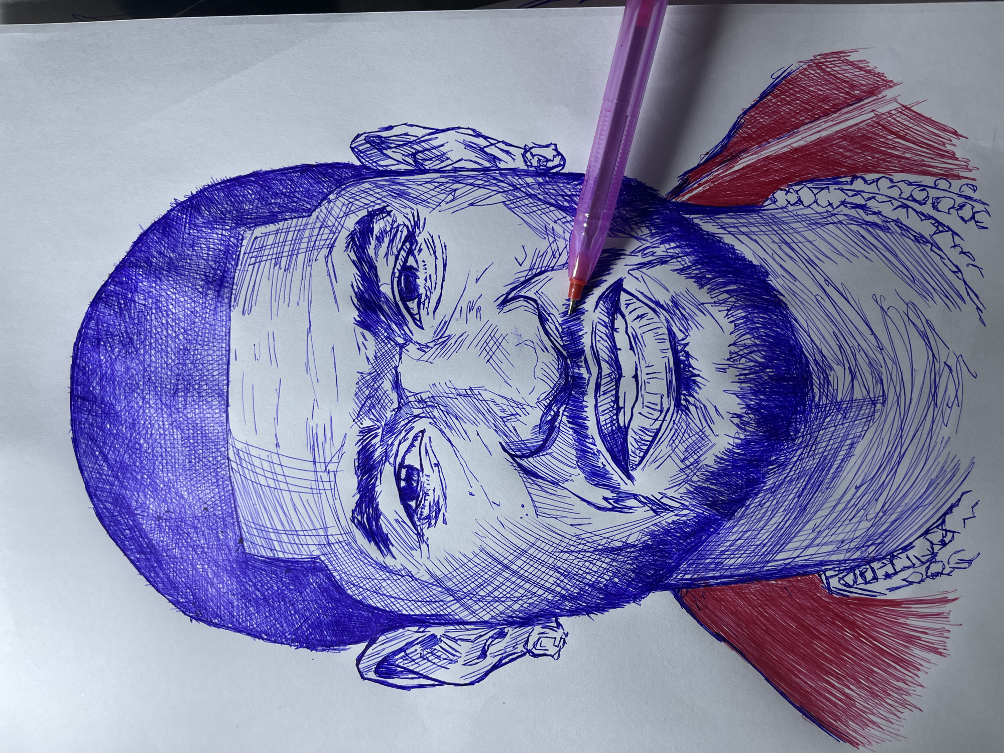 This is a close-up, eye-level shot of a pen-and-ink drawing of a man's face. The drawing is done in blue and red ink on white paper. The man has short hair, a beard, and is wearing earrings and a chain necklace. The drawing is detailed, with hatching used to create shading and texture. A pink pen is positioned across the man's mouth, obscuring part of his lips. The background is plain white paper. The image does not contain any elements that would allow for the identification of a location in Jos, Nigeria.