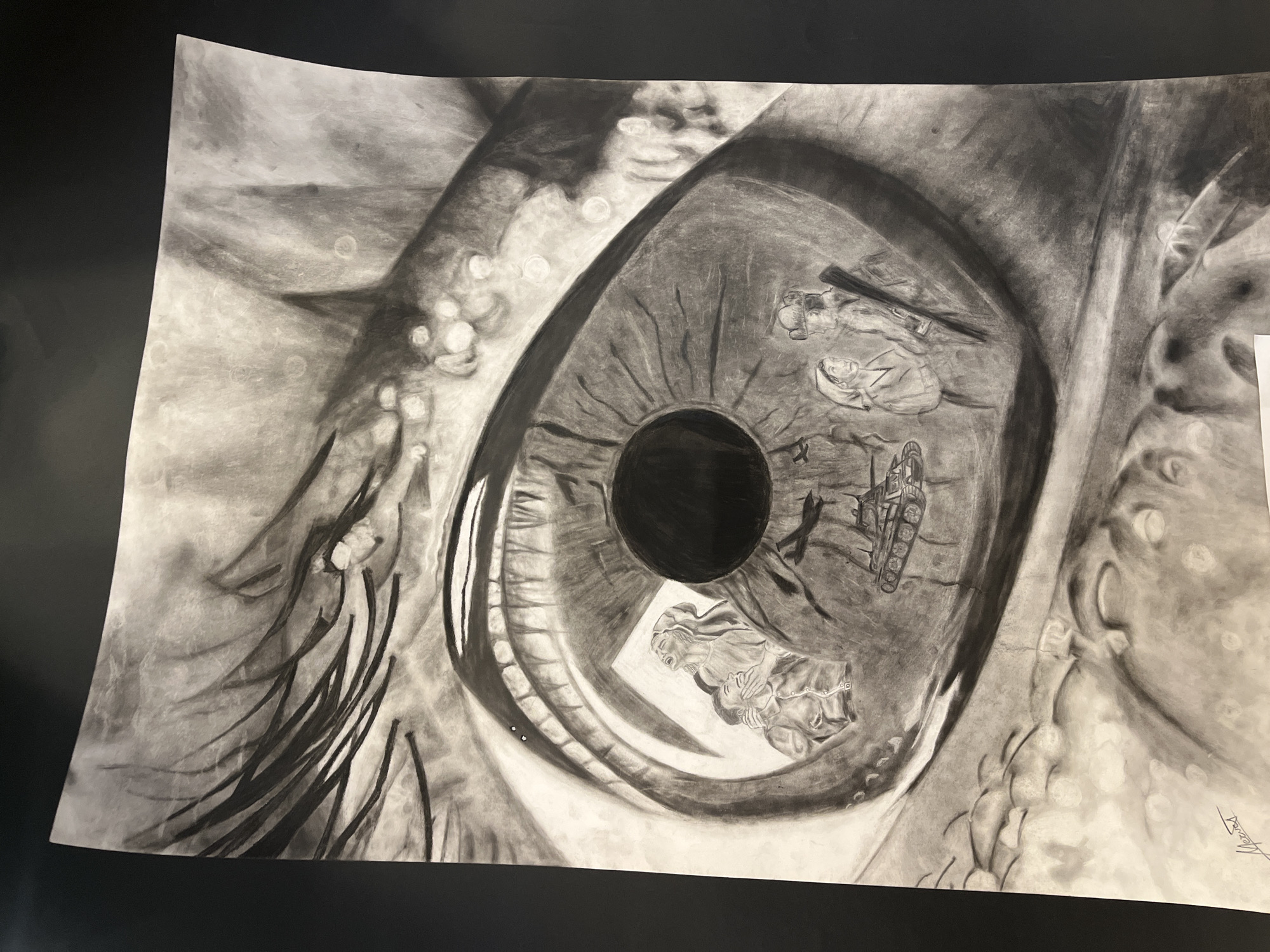 This image is a detailed monochromatic charcoal drawing, featuring a striking close-up of a human eye. The central focus is the iris, which is intricately filled with miniature scenes suggesting conflict and human hardship. Within the iris, an armored tank or military vehicle is visible, along with several figures. One scene depicts a woman embracing or comforting another individual, possibly a child, while another figure appears to be fallen or kneeling near a rifle. Elements resembling barbed wire or broken structures contribute to the somber narrative embedded within the eye.
The pupil is rendered as a deep, solid black circle. The surrounding sclera and skin are meticulously detailed, with visible eyelashes and the texture of the eyelid and brow area. Several circular white highlights are scattered across the sclera and around the eye, possibly representing reflections, tears, or moisture, adding to the emotional depth of the piece. The overall mood conveyed by the artwork is one of reflection, sorrow, or observation of profound events.
The medium, charcoal, allows for a rich range of tones from stark black to soft grays, enhancing the dramatic and poignant quality of the imagery. A signature, possibly "Miroslava," is visible in the bottom right corner of the drawing. This artwork originates from Asenovgrad, Bulgaria.