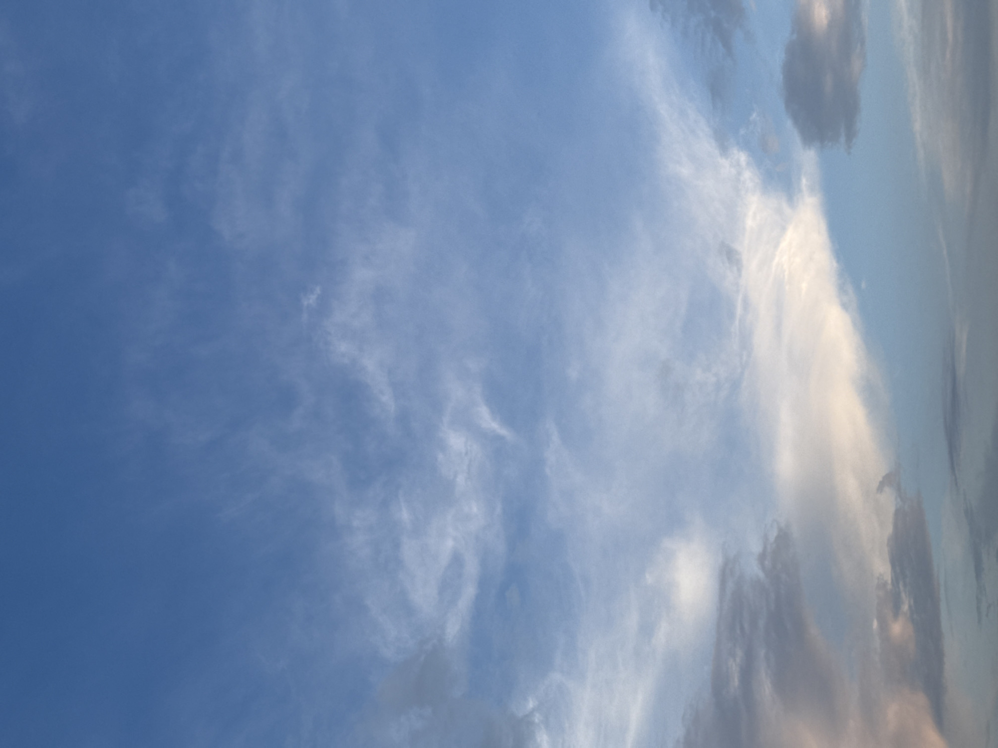 This is an image of the sky with scattered clouds. The sky is predominantly blue with wispy white and gray clouds. There is no indication of the city of Zarechnaya (Gamovskoe S/P), Russia, within the image itself. The scene is purely atmospheric.