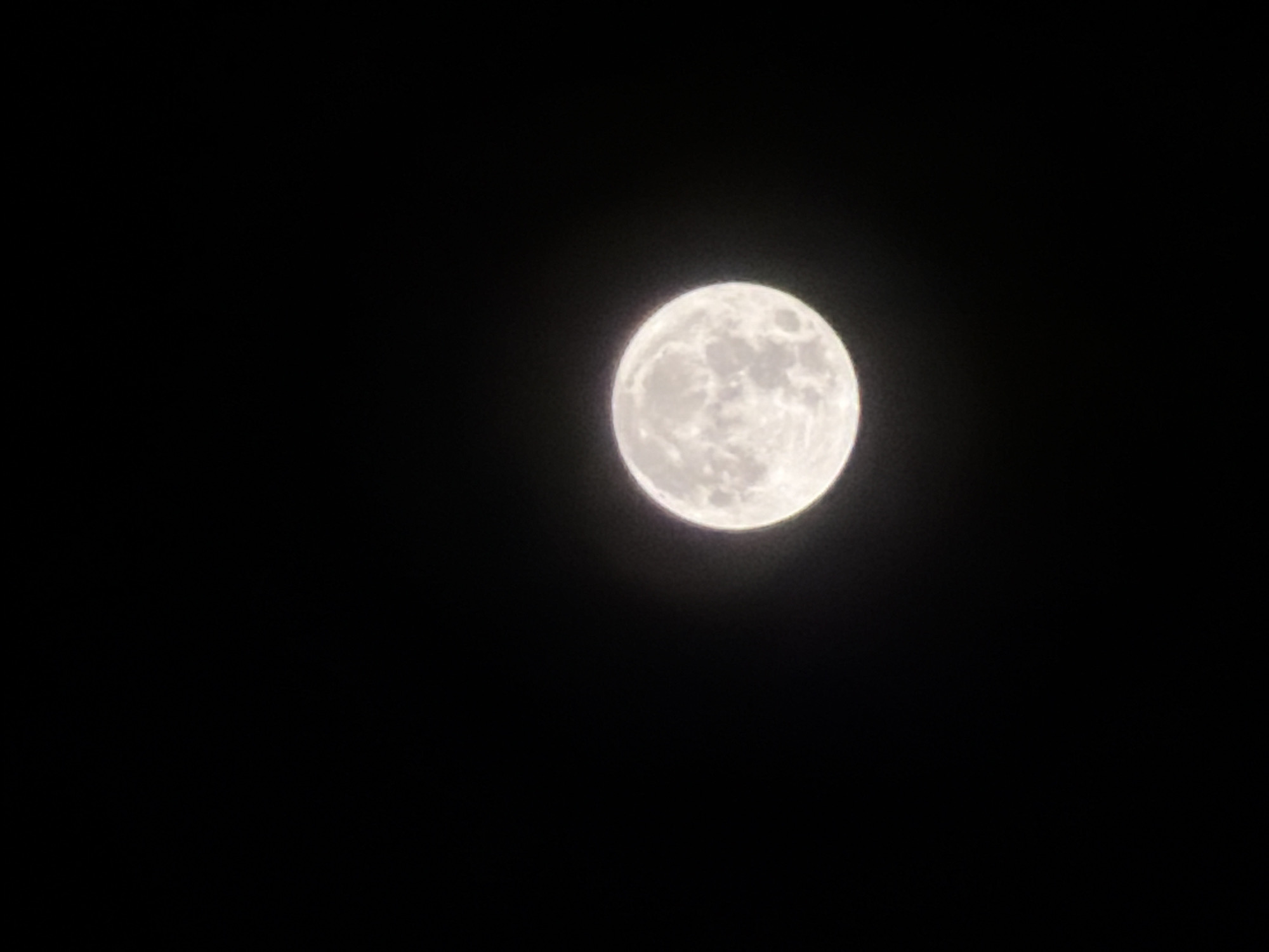 A full moon shines against a black sky. The moon is centered on the right side of the frame and appears to be a gibbous moon. The image does not contain discernible details that could pinpoint a location in Đà Nẵng, Vietnam. There are no people, subjects, objects, actions, or interactions besides the presence of the moon. The environment is a night sky.