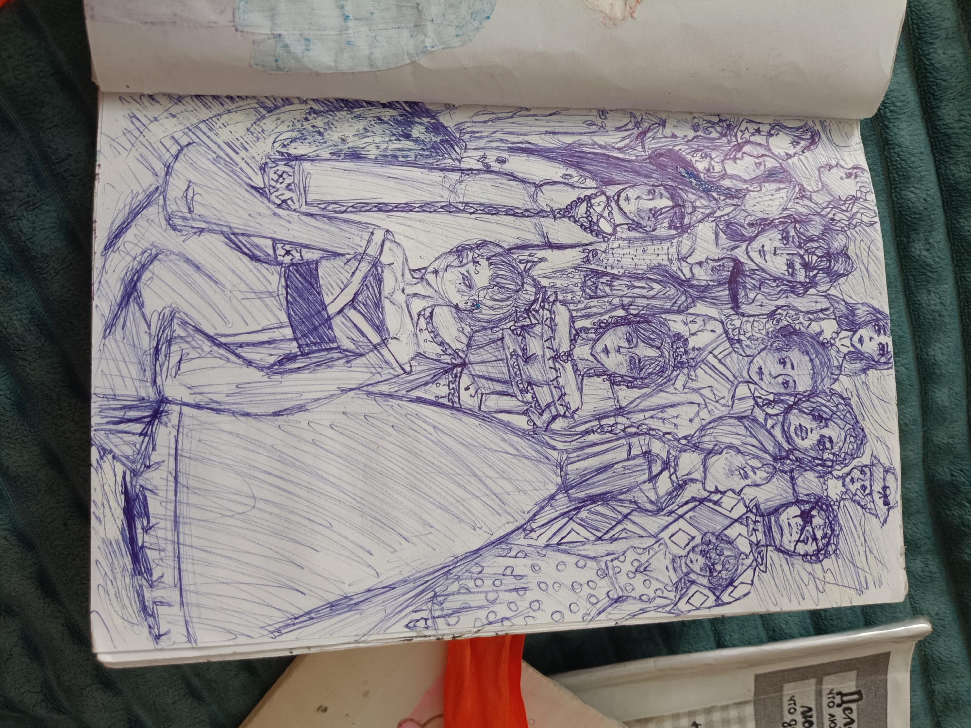 The image is a close-up, overhead shot of an open sketchbook lying on a dark green textured surface, likely a blanket or upholstery. The sketchbook page is filled with a detailed pen-and-ink drawing rendered in dark blue ink. The drawing depicts a crowded composition of figures, primarily faces and upper bodies, with a focus on intricate clothing and hairstyles. The style is sketchy and gestural, with rapid lines used to define forms and create shading.
The figures appear to be a mix of male and female, with varied expressions and poses. Some are looking directly at the viewer, while others are depicted in profile or with their faces turned away. There is a sense of a narrative or a gathering, with the figures overlapping and intertwining. The clothing suggests a historical or fantasy setting, with elaborate collars, headwear, and patterned fabrics. One prominent figure in the foreground on the left is depicted with a large, flowing garment.
The sketchbook itself appears to be well-used, with some slight creasing and a few faint smudges of color, possibly watercolor, near the top edge of the page. The lighting is diffused, highlighting the texture of the drawing and the surrounding surface.
The question about the "location in the city of Посад, Russia" is not supported by any visual evidence in the image. The image is a close-up of a drawing in a sketchbook and does not contain any recognizable landmarks, signs, or contextual elements that would place it in any specific geographical location, including Посад, Russia.
