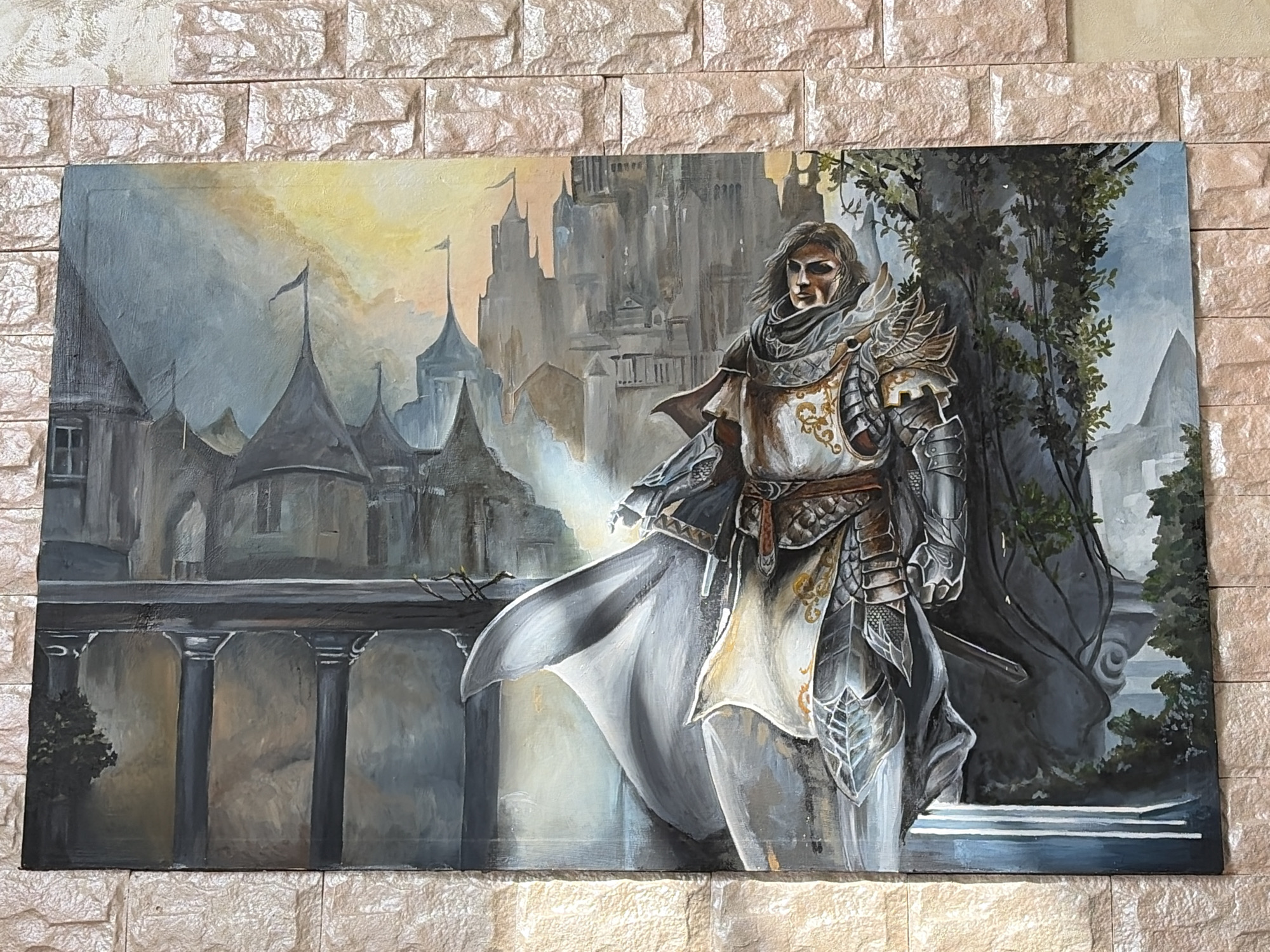The image shows a painting of a knight in armor standing in front of a castle. The knight is wearing a white tunic with gold embroidery, and his armor is silver and gold. He is holding a sword, and his cape is blowing in the wind. The castle in the background is tall and imposing, with many towers and turrets. The painting is hanging on a brick wall. There is no indication of the location being Neftekamsk, Russia.