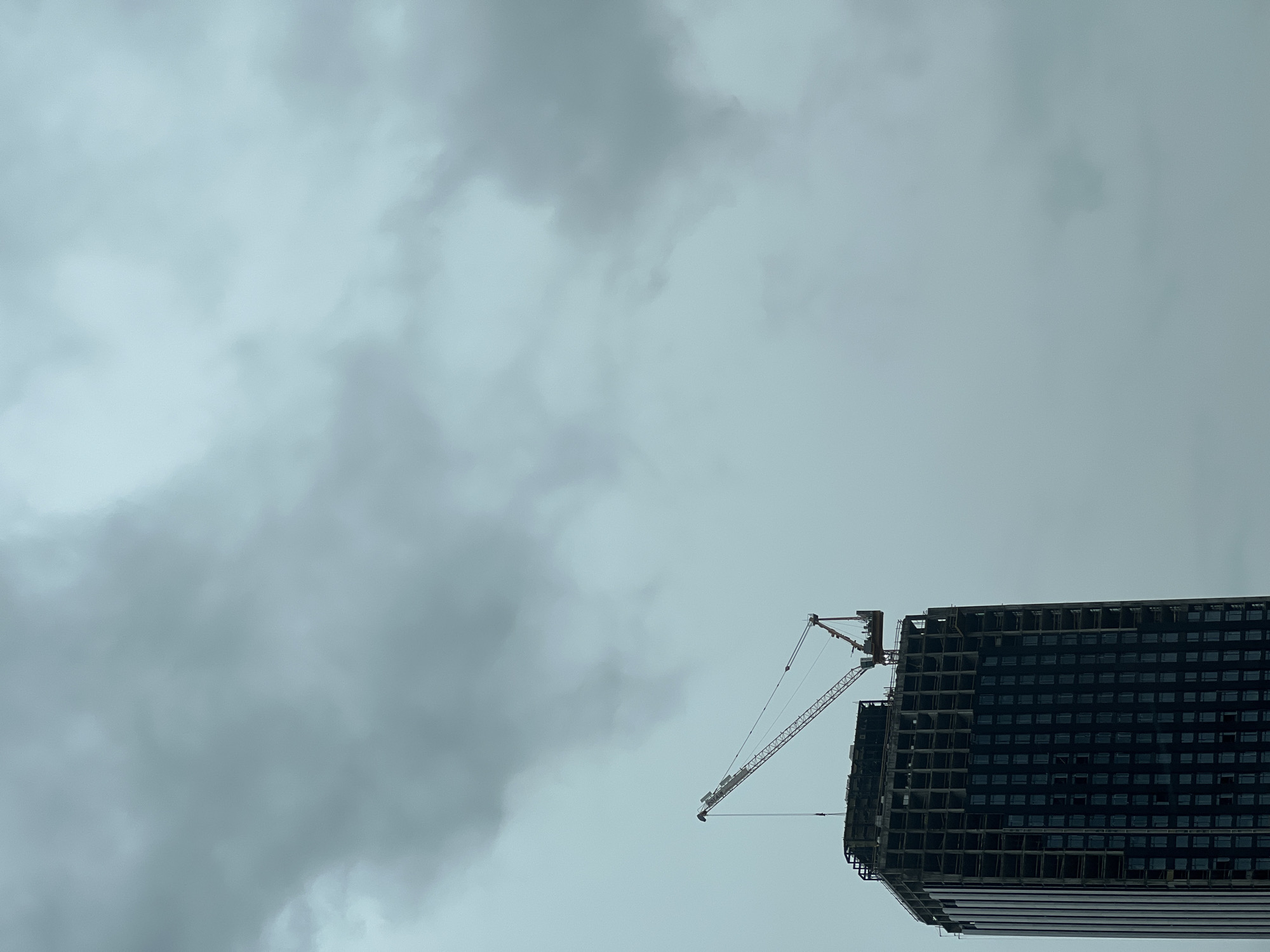 The image shows a cloudy sky over a high-rise building under construction. A crane is attached to the building. The city and specific location of Khimki, Russia are not identifiable in the image.