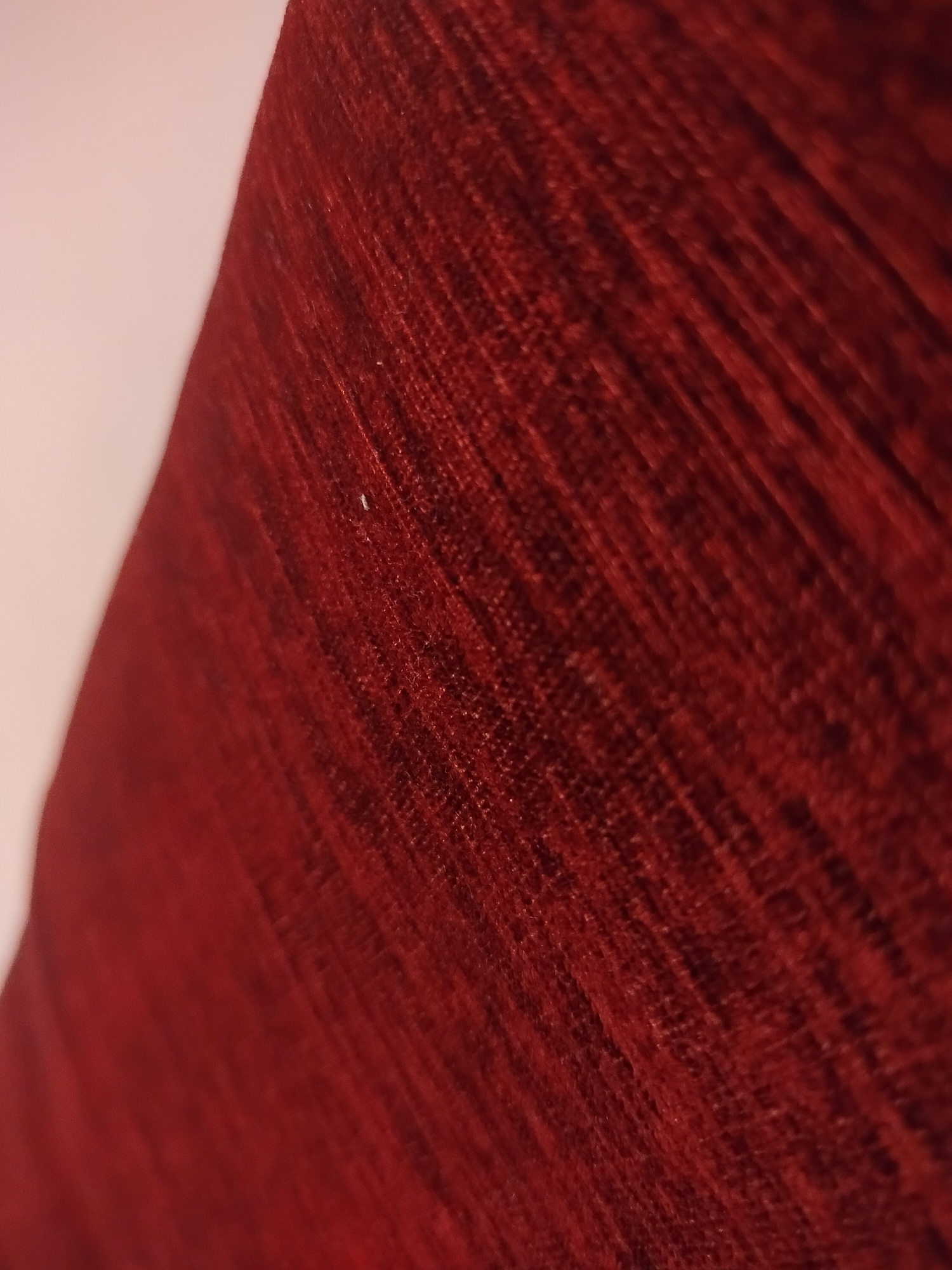 The image shows a close-up of a textured, reddish-brown fabric. The weave of the fabric is visible, creating a linear pattern. The fabric appears to be draped or folded, as indicated by the changing angles and light on the surface. There are no people, subjects, actions, or interactions visible in the image. The environment is not identifiable beyond the fabric itself. The location in the city of Yerevan, Armenia is impossible to ascertain from the image.