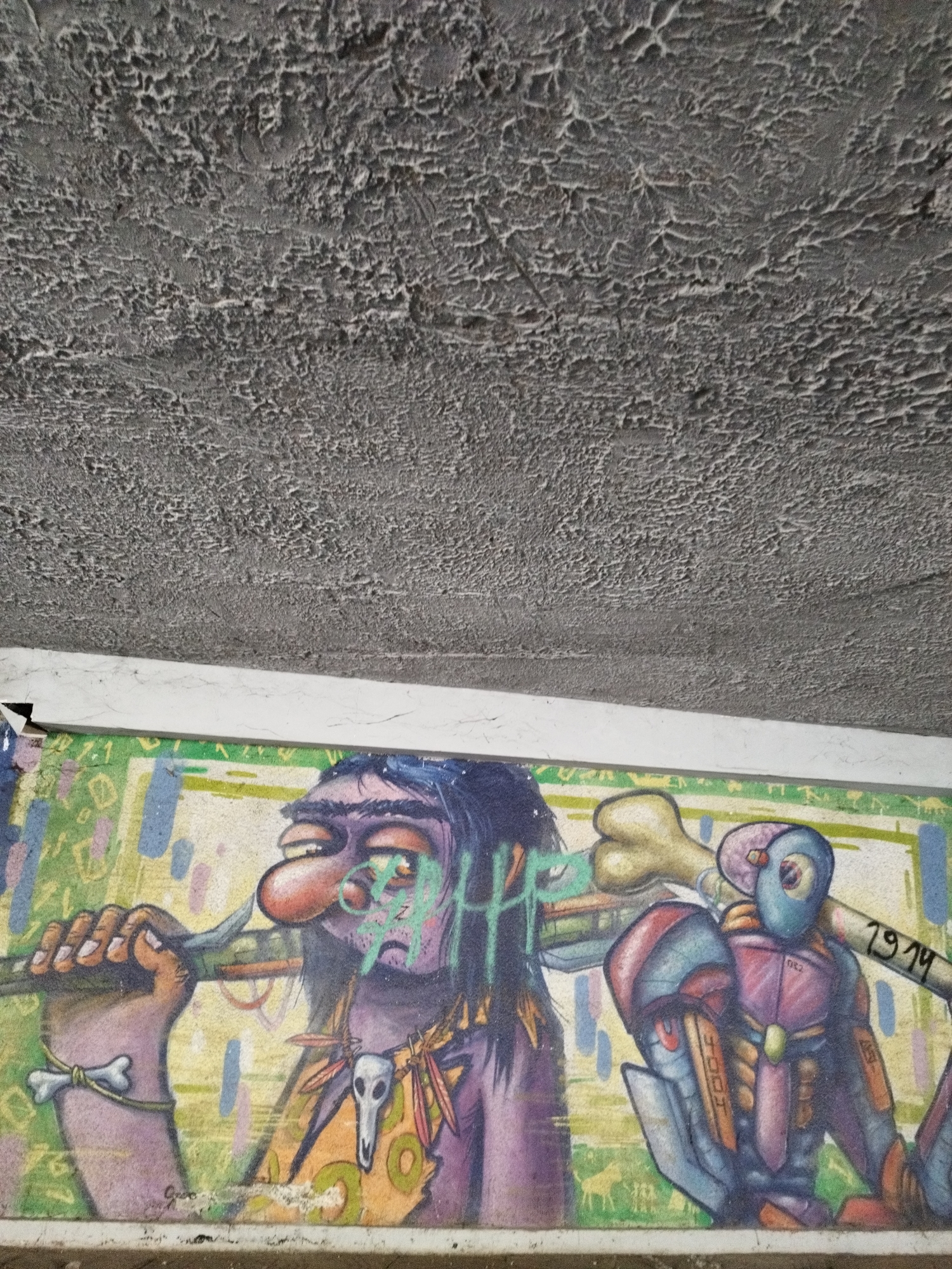 Graffiti art under a concrete ceiling depicts a caveman-like figure with a bone flute alongside a robot carrying a bone. Located in Sofia, Bulgaria.