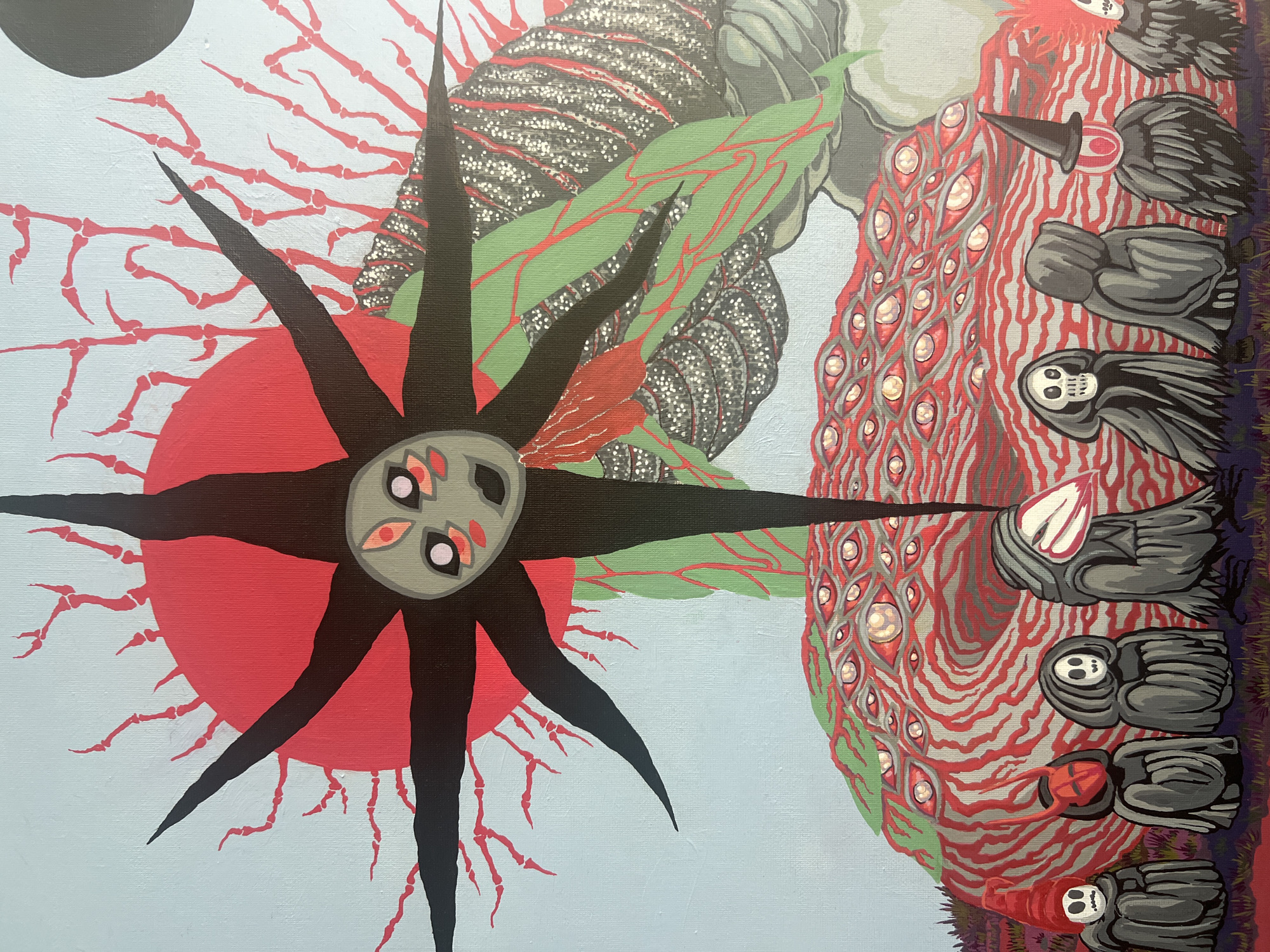 This is a surrealist painting on canvas with a light blue background. The central focus is a black, star-shaped entity with sharp points extending outwards. Within the center of this star shape is a stylized face with four eyes, two large and two small, all with pinkish irises and black pupils. A large red circle, resembling a sun, is positioned behind the star entity, with thin, red, bone-like structures radiating from it.
In the foreground, a large, mound-like object dominates the lower portion of the painting. This mound is covered in a pattern of red and grey swirling lines, and appears to be composed of numerous eyes, each with a white iris and red pupil, some with highlights suggesting wetness.
Below this eye-covered mound, a line of figures stands. These figures are cloaked and have stylized, skeletal or mask-like faces. One figure on the far left has a red conical hat and a skull face. Next to it is a figure with a red mask with black horns. Other figures wear grey hoods and have skull faces, or a beak-like protrusion. One figure wears a black pointed hat. The ground they stand on is a mottled purple and red, with sparse, dark green and red vegetation.
To the right of the main mound, there are large, green, leaf-like shapes with red veining, and a textured, grey and white object with red striations. A black circular object is visible in the upper right corner of the painting.
The painting does not depict any recognizable landmarks or scenes from Karon, Thailand. It is a fantastical and symbolic artwork.