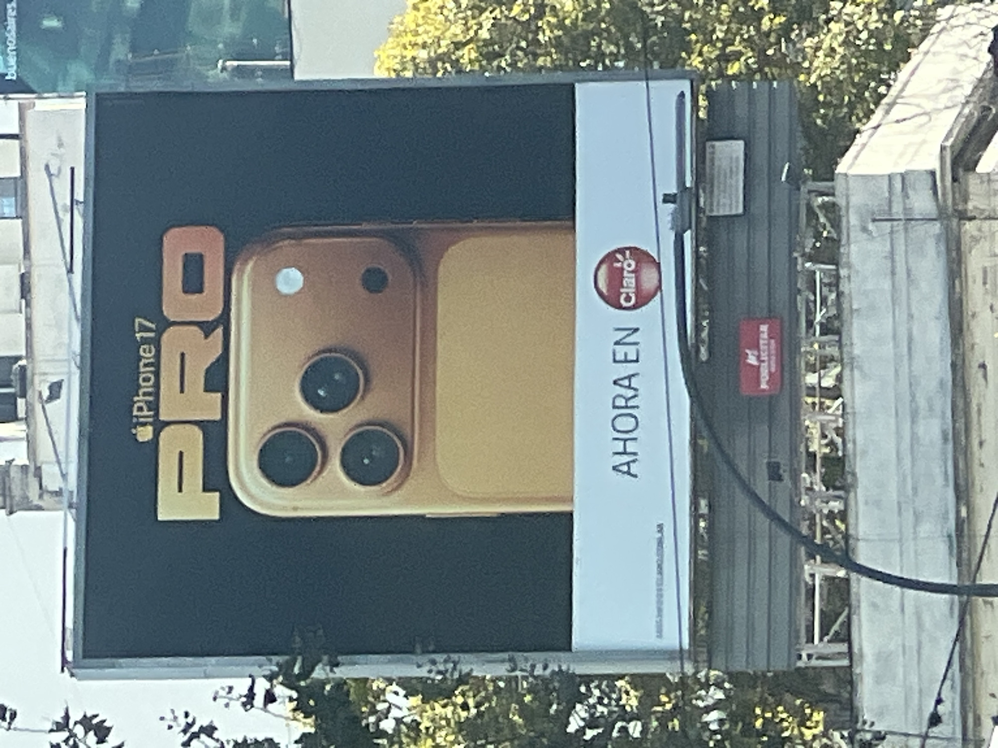 The image depicts a billboard ad for the iPhone 17 Pro. It is an outdoor advertisement by the Claro communications company. The surrounding environment contains buildings and trees. Parts of the word "Buenos Aires" are visible on the top left corner of the image, confirming the location as Buenos Aires, Argentina.