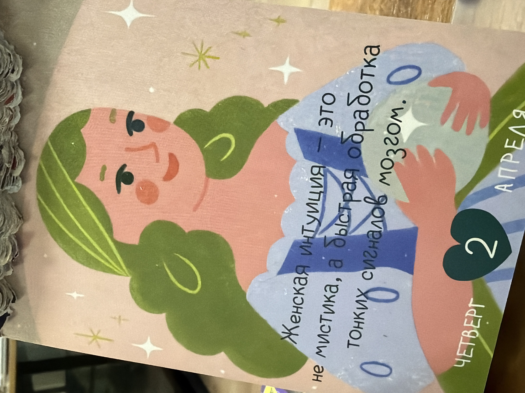 The image shows a cartoonish illustration of a woman with green hair and a peach-colored complexion. She is holding a pale blue sphere. The background is light pink with stars. Text in Russian is written on the right side of the image, with the word "АПРЕЛЯ" (April) visible. A number "2" is inside a dark green heart shape. The word "ЧЕТВЕРГ" (Thursday) is printed below. The image seems to be a calendar or a card related to a date in April, specifically Thursday, April 2. There is no location in the city of Moscow, Russia, in the image.