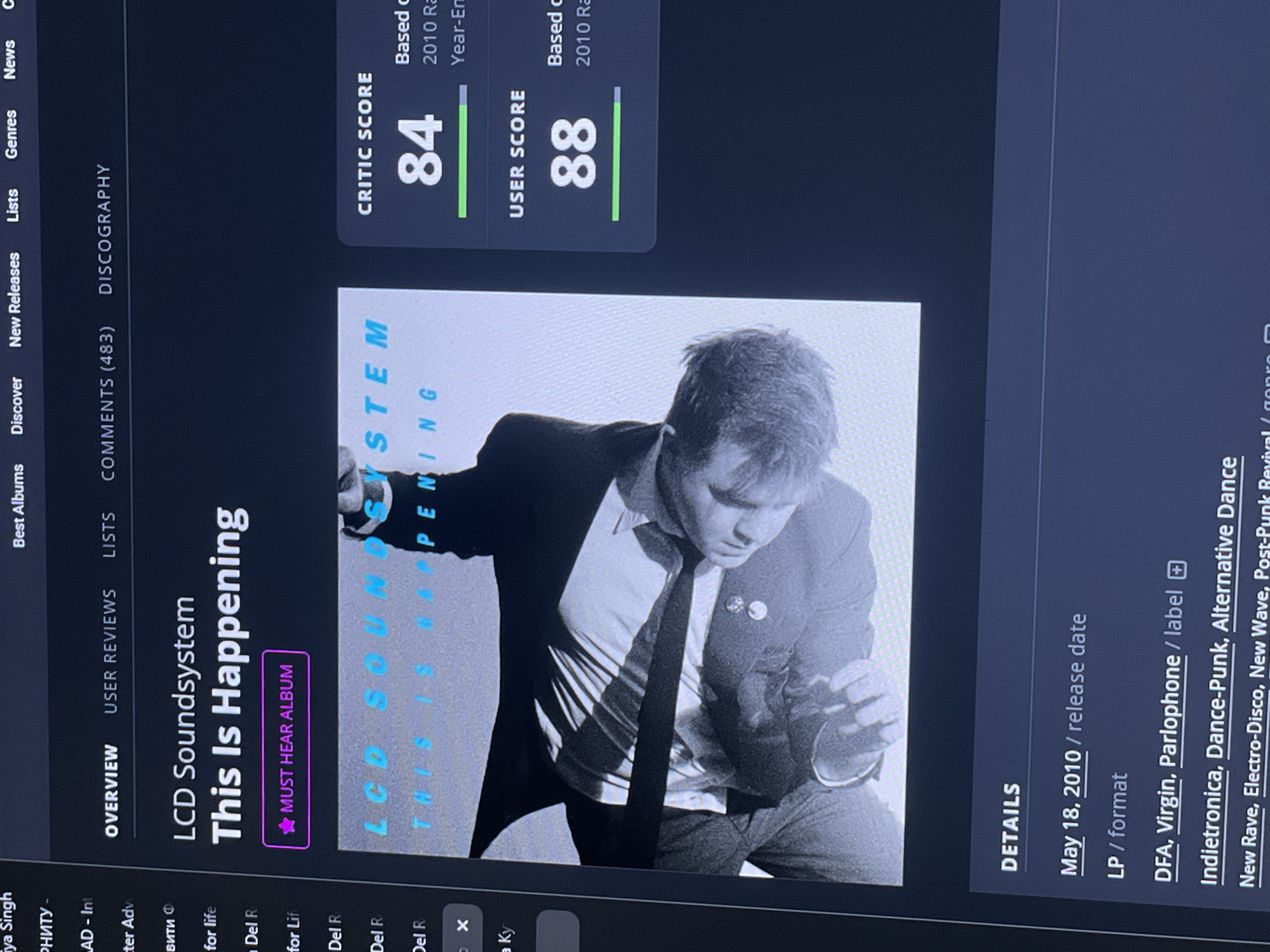 The image shows a computer screen displaying a webpage for the album "This Is Happening" by LCD Soundsystem. The webpage includes album art, critic and user scores, and release details. The album art is a black and white photograph of a man in a suit and tie. The critic score is 84 and the user score is 88. The release date is May 18, 2010. The format is LP. The labels are DFA, Virgin, and Parlophone. The genres include Indietronica, Dance-Punk, Alternative Dance, New Rave, Electro-Disco, and New Wave. There is no information in the image that would indicate its location in the city of Angarskie Khutora, Russia.