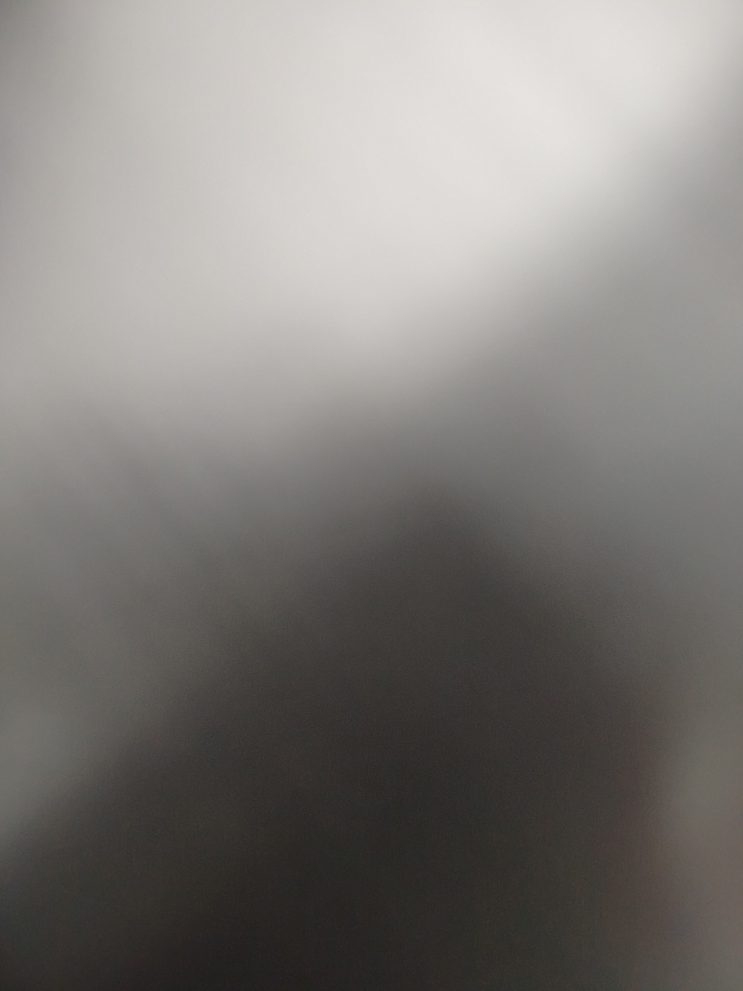 The image is an out-of-focus shot, transitioning from a light grey at the top to a dark grey at the bottom. There are no discernible objects, people, or identifiable environmental details. Therefore, it is impossible to determine the location, specifically in Yerevan, Armenia.