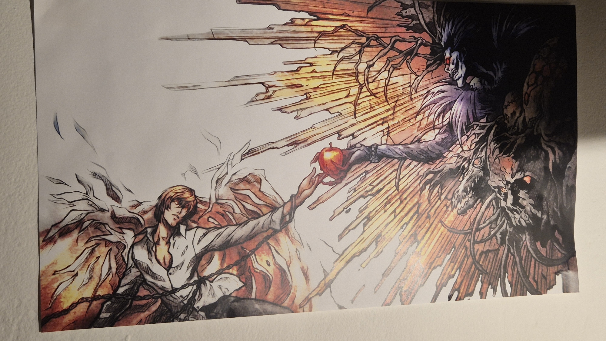 The image is a poster of an anime illustration. On the left, a man with blonde hair, wearing a white shirt, is depicted with fiery wings. On the right, a creature with dark hair, red eyes, and a monstrous appearance is reaching out with an apple. The two figures appear to be exchanging or offering the apple. The background features fiery orange and yellow streaks, suggesting a dramatic or supernatural scene. The poster is hanging on a plain white wall, likely in a room. The location is not discernible from the image itself, and therefore cannot be identified as Sofia, Bulgaria.