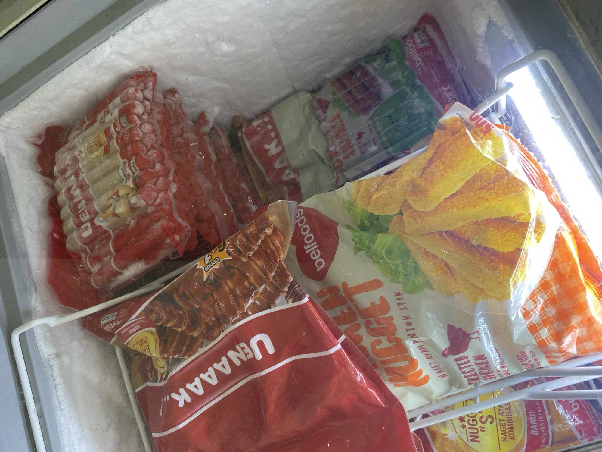 This image shows the interior of a commercial freezer filled with various frozen food products. The products are mostly packaged in plastic wrappers and include sausages, chicken nuggets, and other processed meats. Some packages are partially obscured by others, but the overall impression is one of a well-stocked frozen food display. The lighting suggests a bright interior, possibly from a freezer lamp. The specific location of Payatieng, Indonesia is not ascertainable from the visual information provided in the image.