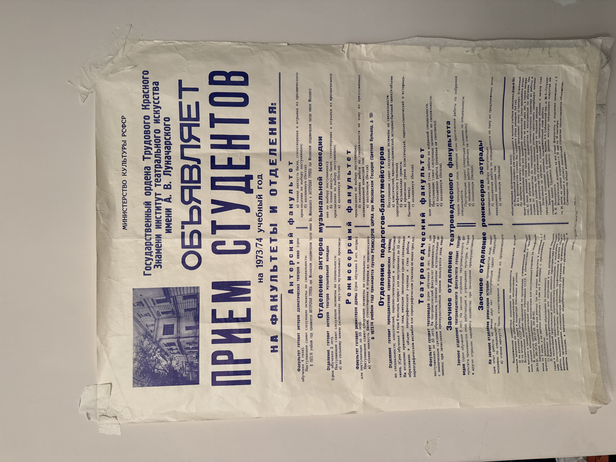 The image shows a poster for the State Institute of Theatre Arts named after A. V. Lunacharsky, located in Moscow, Russia, at 6 Sobinovsky Lane. The poster advertises student admissions for the 1973/74 academic year. It lists the faculties and departments available, including Acting, Musical Comedy Acting, Directing, Teacher-Ballet Masters, and Theatre Studies. The poster provides details on the entrance exams required for each program. It also gives instructions for submitting applications and required documents. The paper is wrinkled and affixed to a surface with tape at the corners. A black and white picture of a building is on the left side of the poster.