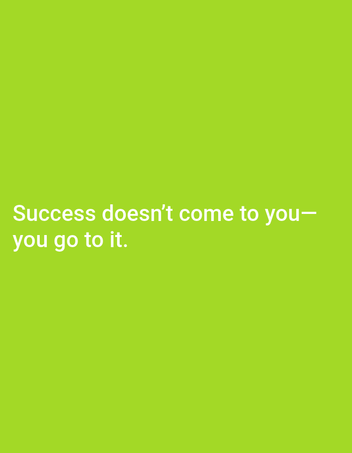 A close-up, eye-level, full shot shows white text on a vibrant, lime-green background. The text reads: "Success doesn't come to you— you go to it." The text is centered on the right half of the frame and is slightly blurred.