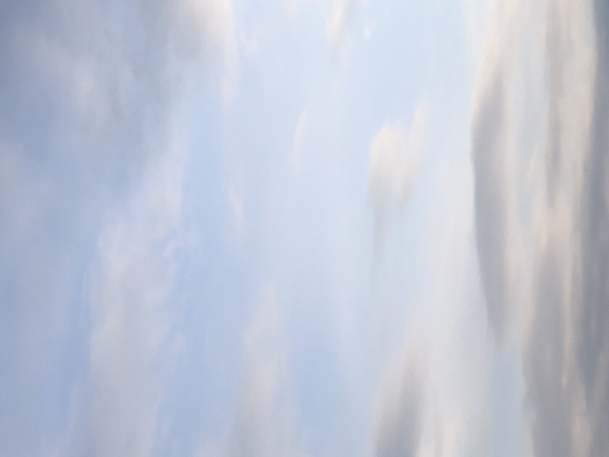 The image shows a sky with clouds. It is difficult to determine the location, date, and time of the photo. The sky is light blue with white and gray clouds scattered across it.