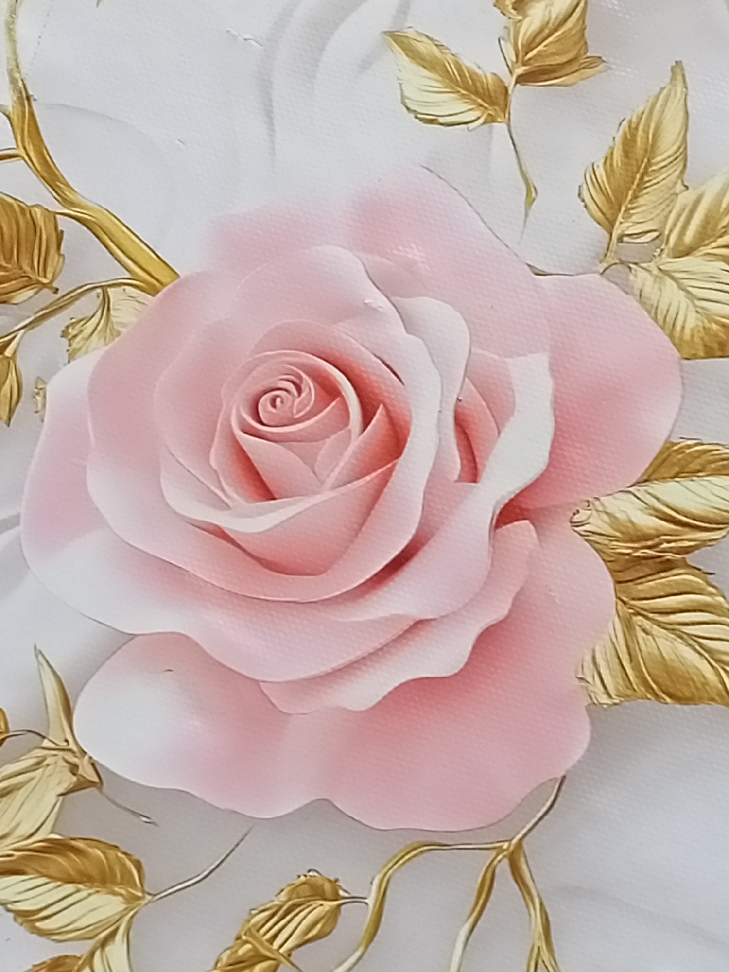 This is a close-up, high-angle shot of a pink rose with gold leaves. The rose is in full bloom, with many delicate petals arranged in a spiral pattern. The gold leaves are depicted with detailed veins and a slightly metallic sheen. The background is a soft, textured white, suggesting a canvas or wall. The lighting is diffused, creating soft shadows that highlight the three-dimensional quality of the rose and leaves. There are no people, actions, or interactions visible in the image, and no specific location in Sokuluk, Kyrgyzstan is identifiable.