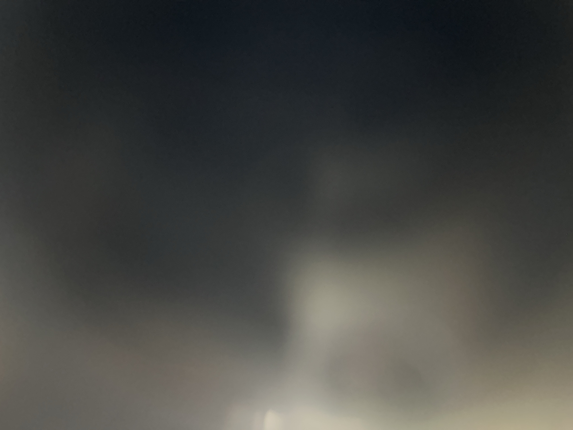 The image is an abstract, out-of-focus photograph with a gradient of dark gray to lighter gray with a hint of white in the lower left corner. There is no discernible city, Belgrade, Serbia, or any identifiable objects, people, or actions present. The image is purely textural and lacks any specific features to describe.
