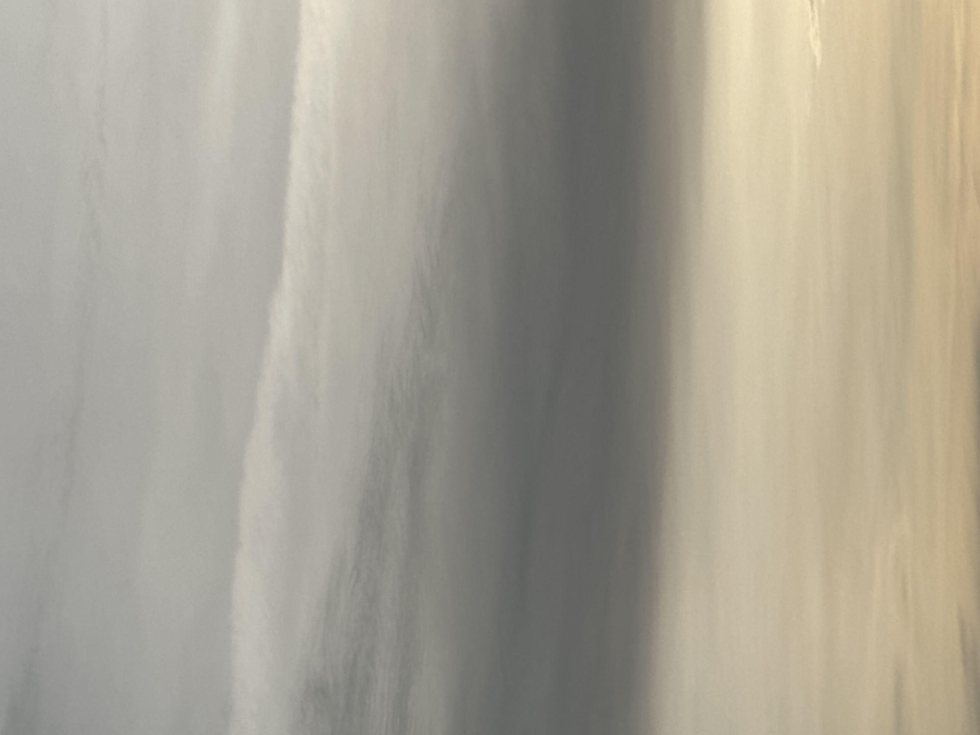 The image shows an abstract, close-up view of what appears to be a textured or flowing surface. The colors range from light gray to darker gray, with hints of beige or yellow in certain areas. The texture suggests either a natural phenomenon, like water or clouds, or an abstract artistic representation. There is no discernable evidence to indicate the location in Nizhny Novgorod, Russia, or any other details regarding people, subjects, objects, actions, or interactions.