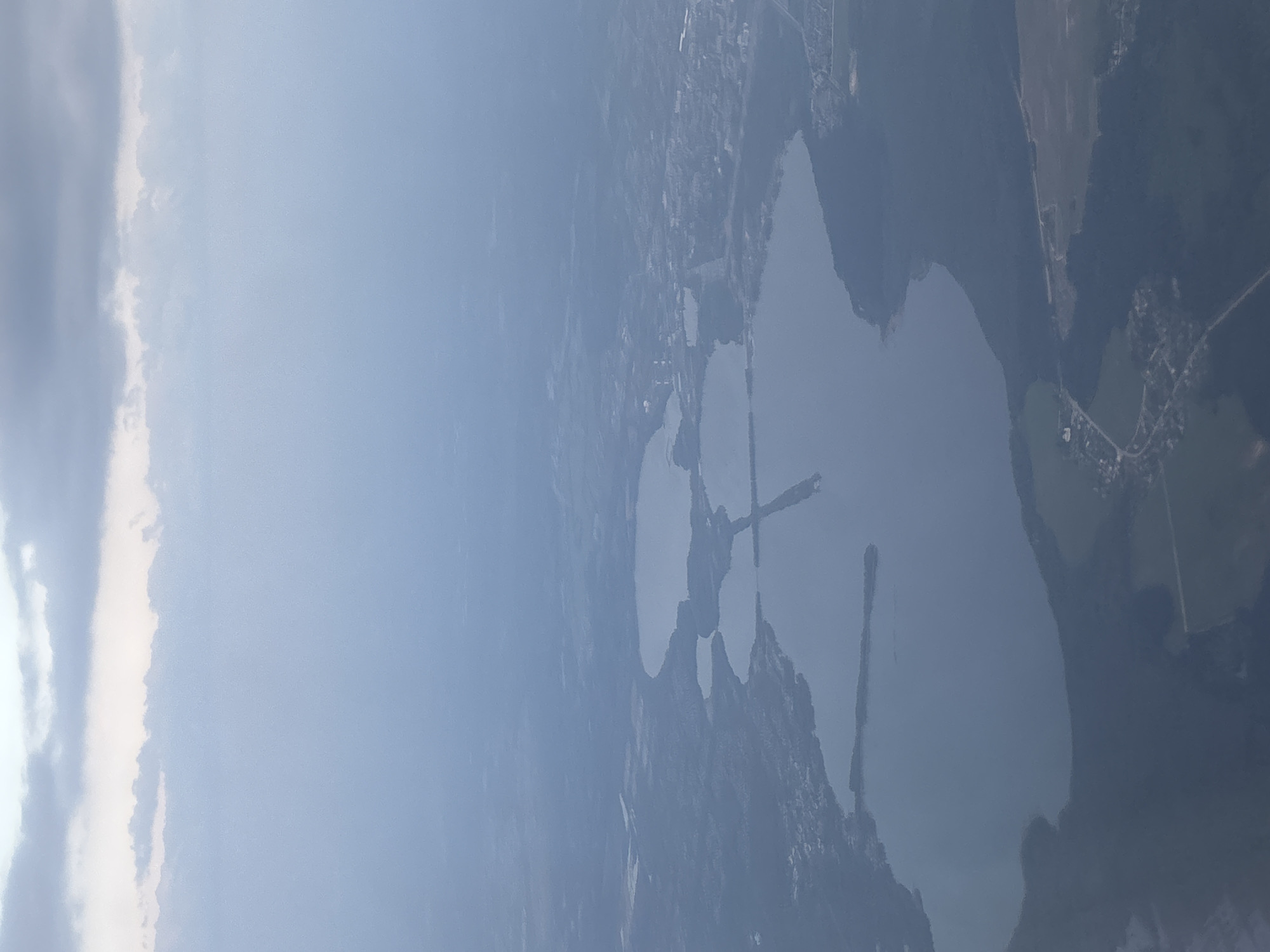 The image shows an aerial view of a lake complex near the city of Бордуки, Russia. The lakes are interconnected by narrow channels and surrounded by dense forests and urban development. The sky is overcast, suggesting a cloudy or hazy day.