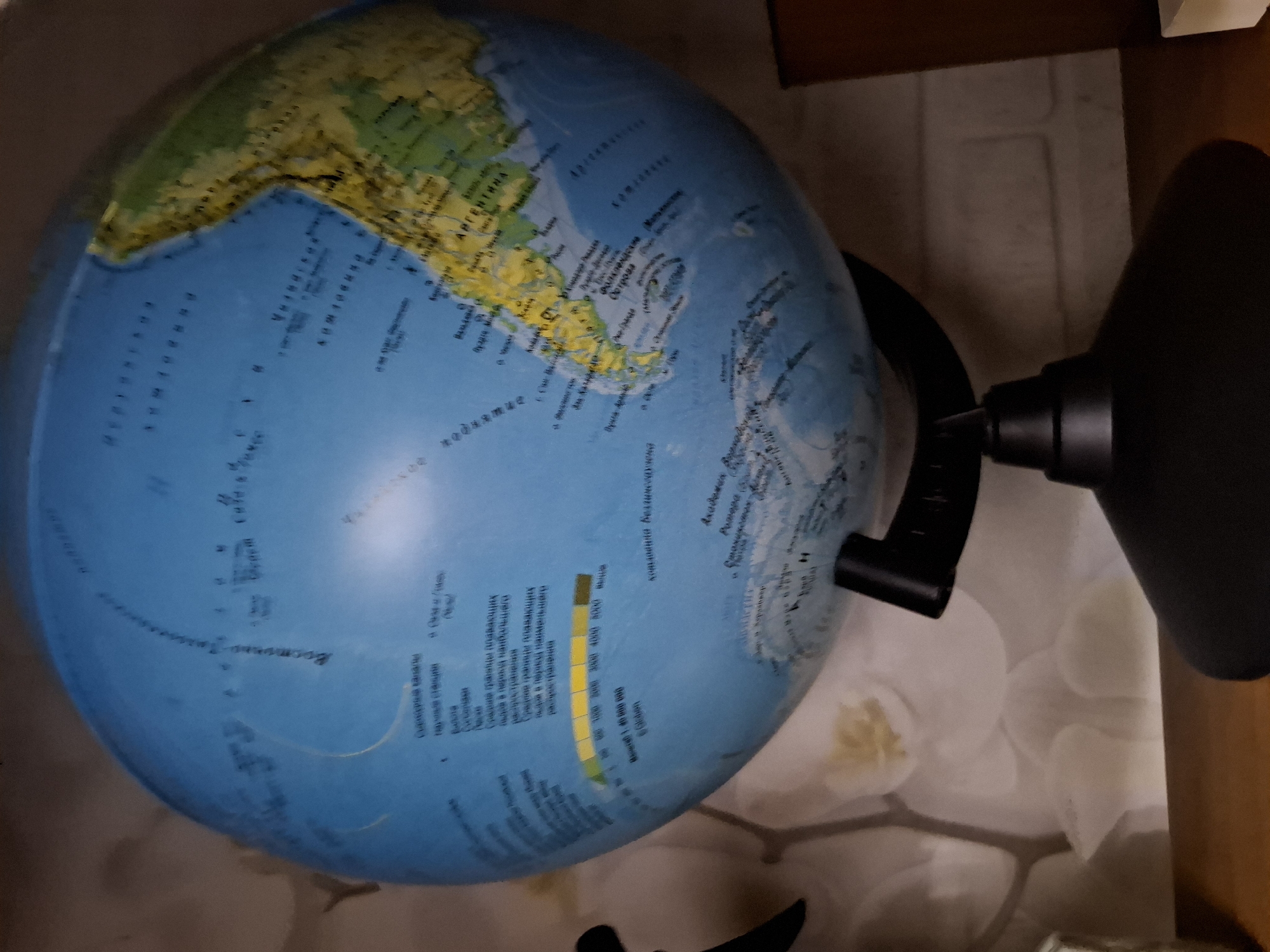 The image shows a globe of the world. The South American continent is prominently displayed. Parts of the globe are labeled in Russian. A depth chart is located on the bottom left of the globe in Russian. The globe is resting on a surface.
There is no evidence to suggest that the image was taken in the city of Amzya, Russia.