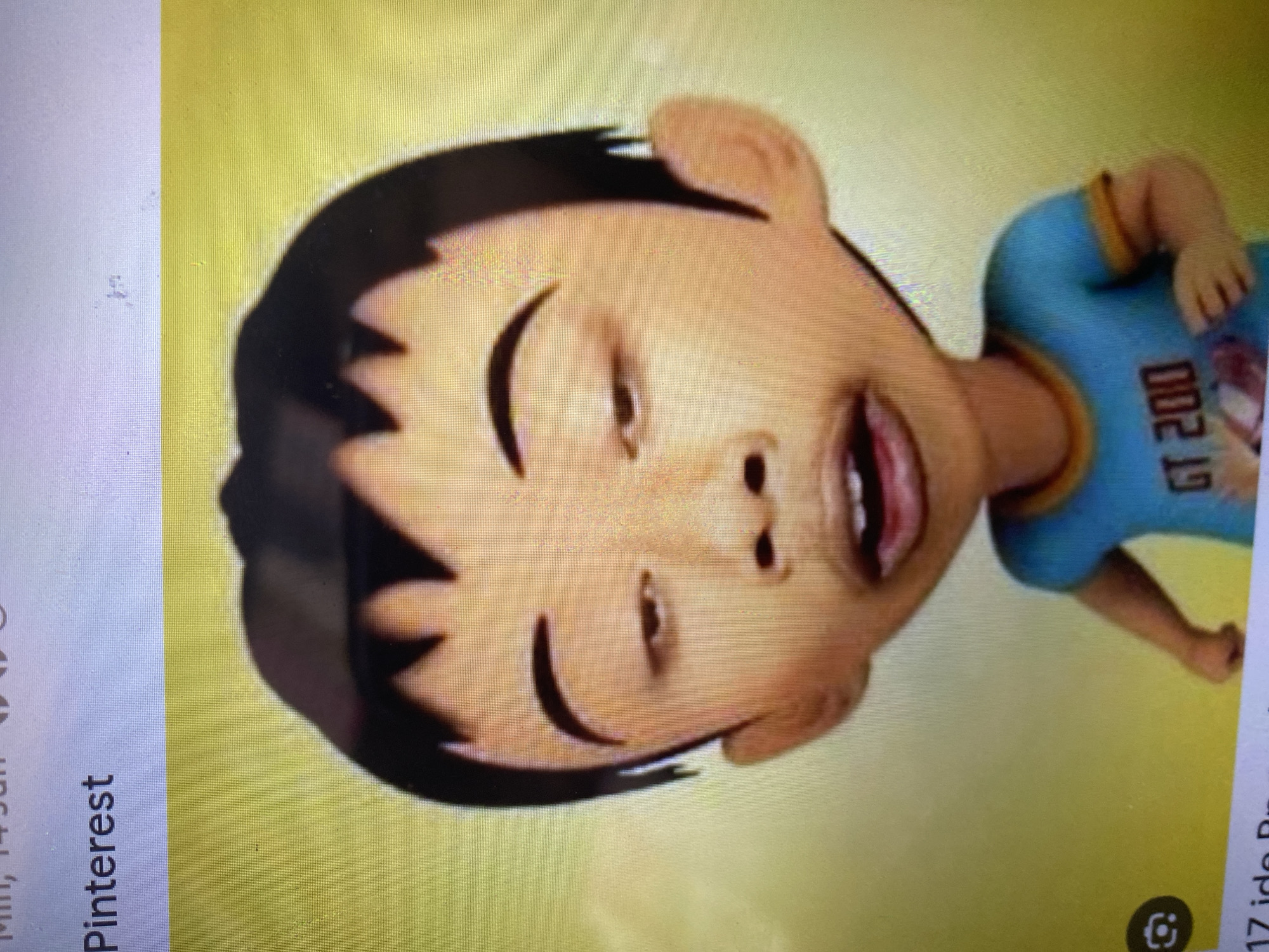 A digitally rendered animated boy with dark hair, prominent eyebrows, and a light-skinned complexion is shown from the chest up. He wears a blue t-shirt with yellow trim and an orange collar, which has the text "GT 200" printed on it. The boy's eyes are partially closed, giving him a tired or sleepy appearance, and his mouth is open, revealing teeth. The background is a gradient of yellow and green, with the upper left corner showing the word "Pinterest" and part of a date which is partially cut off. There is no identifiable city, location, or context provided within the image itself to indicate it is from Ta', Indonesia.