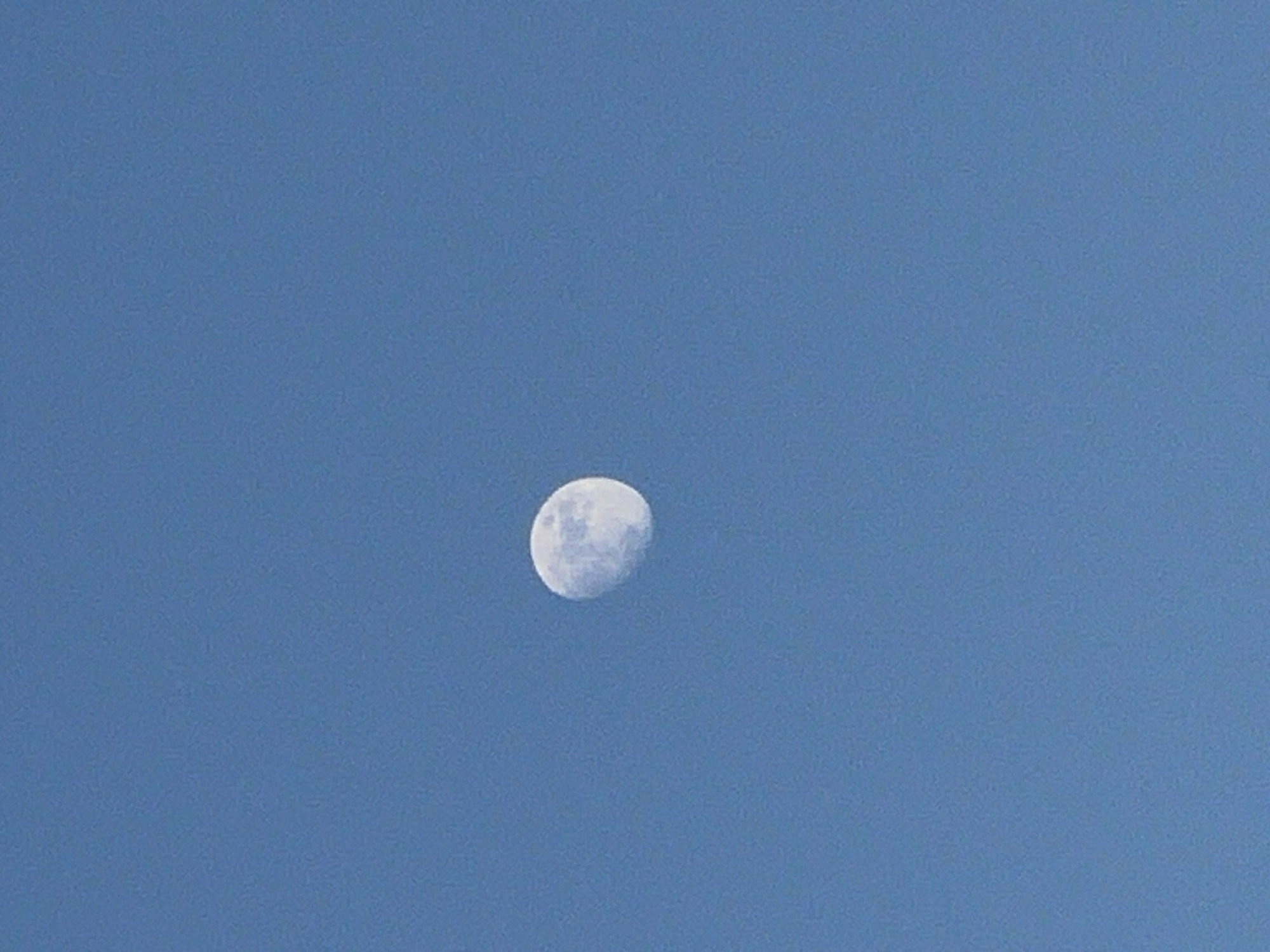 The image shows a waxing gibbous moon in a clear, light blue sky. There are no other objects visible in the frame. The location is unknown, and there is no indication it is Plovdiv, Bulgaria.