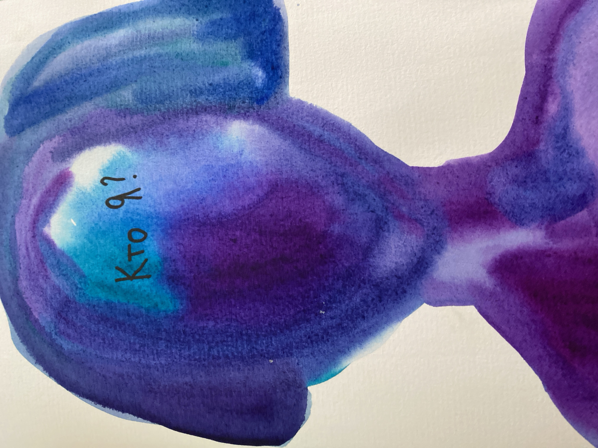 A watercolor painting on white paper depicts a shape reminiscent of a fish or a tadpole, colored in varying shades of blue and purple. The head of the shape is towards the left side of the image, and the tail extends to the right. The text "Кто я?" (Who am I?) is written in dark blue or black ink within the head area of the shape. The painting style is loose and abstract, with visible brushstrokes and color gradients. The image appears to be a close-up shot of the painting. There is no information about the location of Lâm Viên - Đà Lạt, Vietnam in the image.