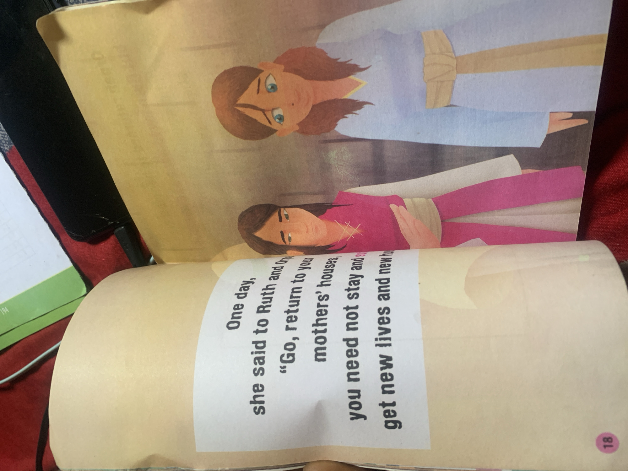 The image shows two illustrated women with brown hair and fair skin. One woman on the left is wearing a pink tunic over a white garment and a yellow sash. The woman on the right is wearing a light blue robe and a yellow sash. Both women have their arms down. There is text on the left page which reads "One day, she said to Ruth and Orpah, 'Go, return to your mothers' houses, you need not stay and get new lives and new homes." The image also shows a pink circle with the number 18 in the bottom left corner. The background is an illustrated interior, possibly a building. The image does not contain any information about Jauro Yinu, Nigeria.