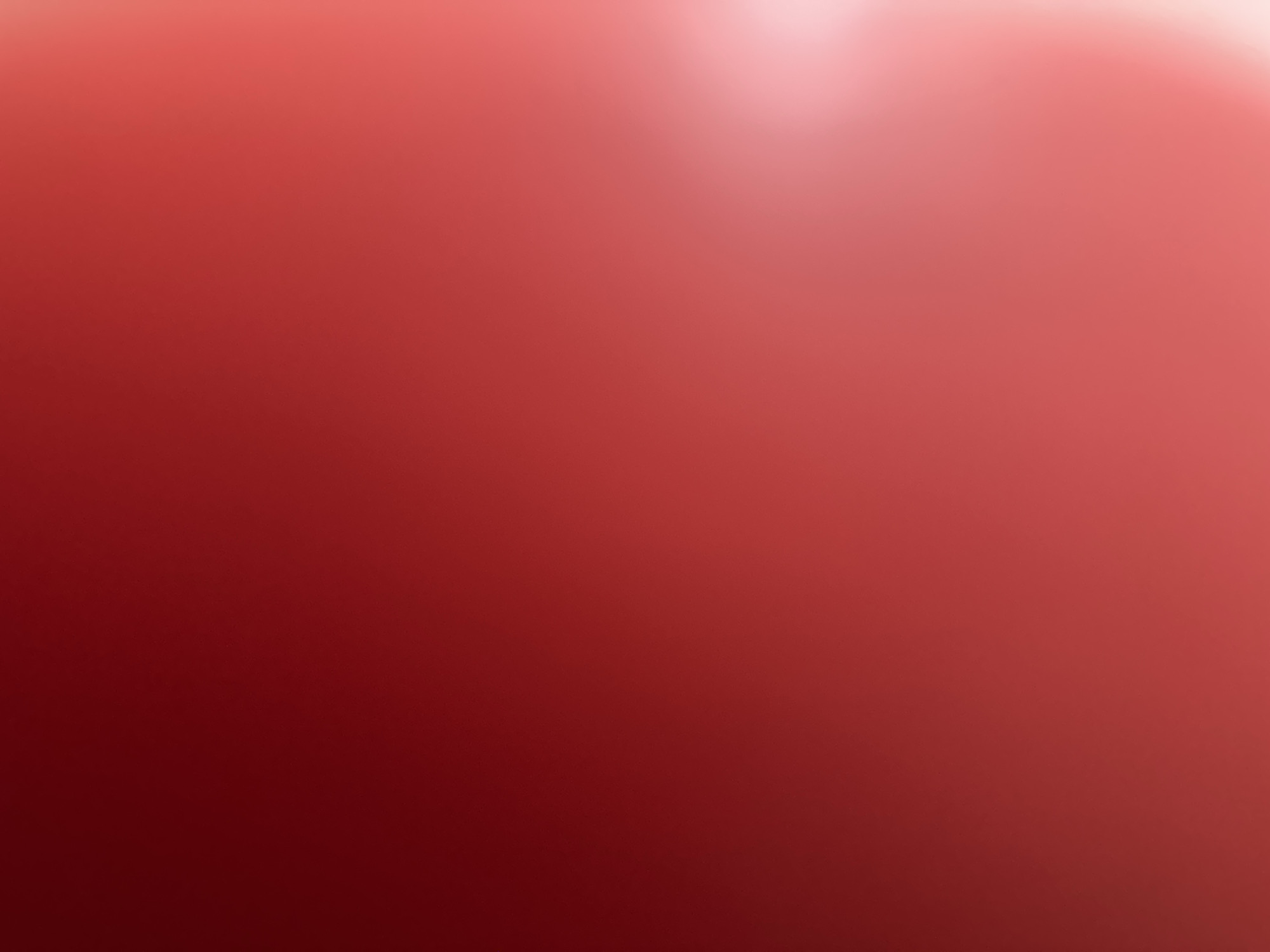 This is an abstract, out-of-focus image dominated by varying shades of red and pink. The lighting creates a gradient effect, with a bright, diffused light source in the upper right corner that fades into darker, richer reds towards the bottom left. There are no discernible subjects like people, objects, or a specific scene. The image does not depict any activity or event. There is no visible text. The abstract nature of the image, combined with the color palette, could evoke a sense of warmth, passion, or a soft glow, but without any concrete elements, the interpretation is entirely subjective. The provided location context of Belgrade, Serbia, does not offer any visual cues to interpret within the abstract image itself. The image is likely a close-up shot of a textured surface, possibly fabric or a painted wall, where the focus has been intentionally blurred.