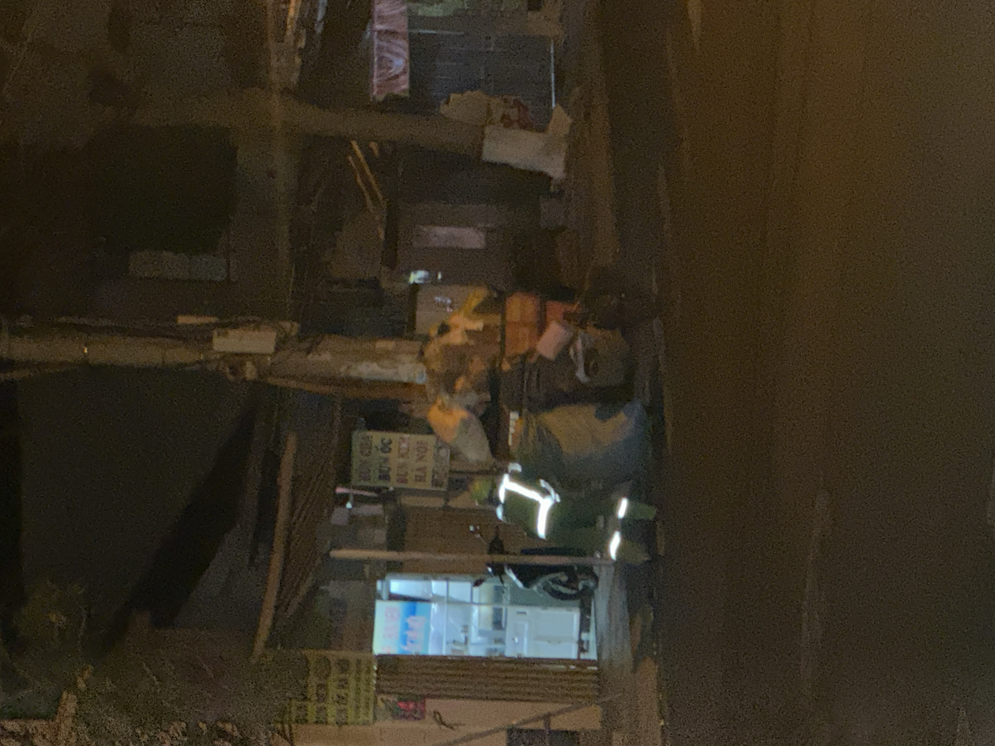 The image shows a street scene in Bac Nha Trang Ward, Vietnam at night. A person wearing reflective stripes is on a scooter. There are buildings on both sides of the street. Signs in Vietnamese are visible. There appears to be a store with lit shelves in the background.