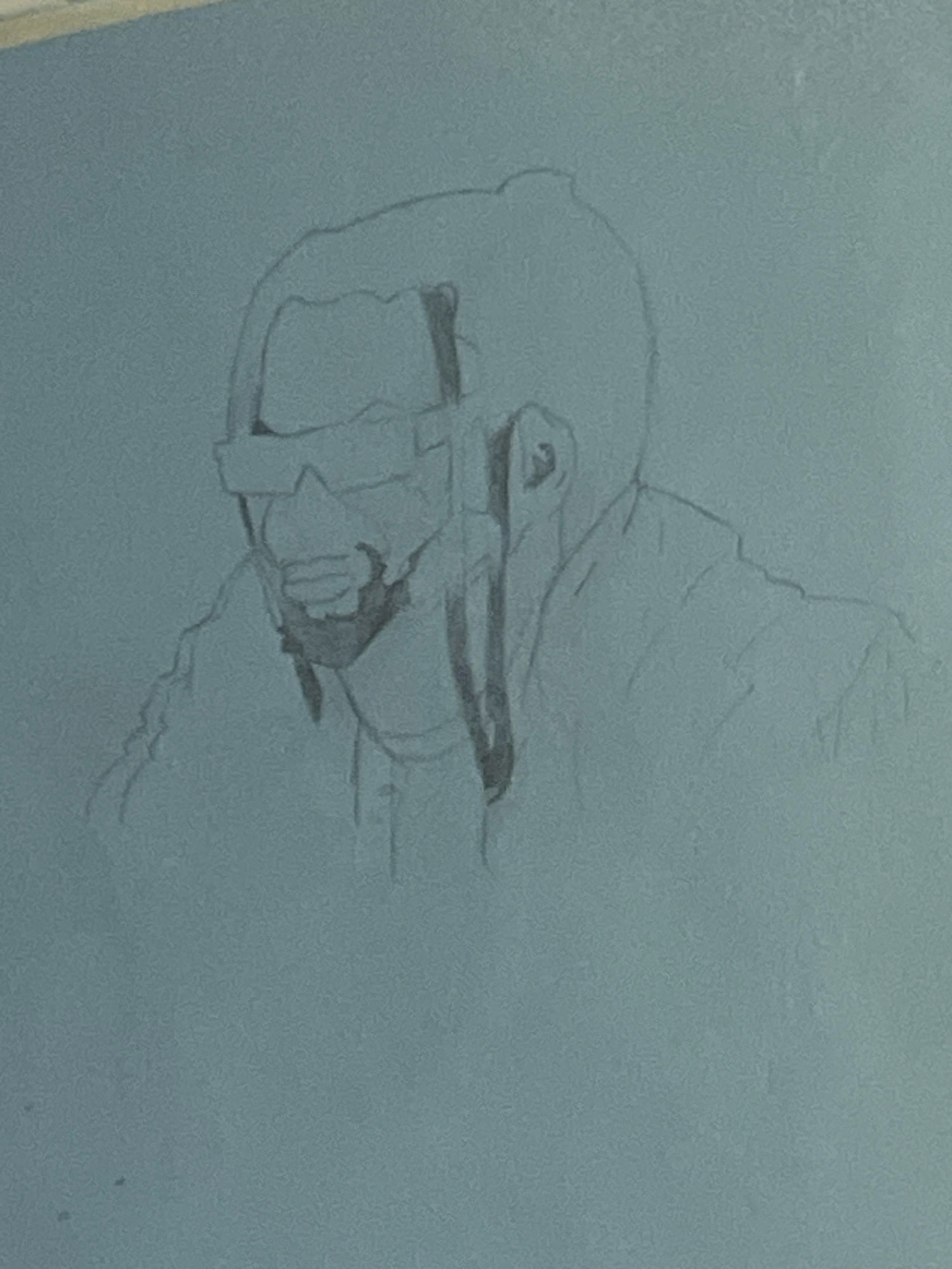 The image shows a pencil sketch of a person's upper body, viewed from the chest up. The person appears to be wearing glasses and has a bun hairstyle with strands of hair falling down. The sketch is done on a light blue surface, possibly paper or canvas. The level of detail suggests a work in progress, with some areas more defined than others. There is no indication of the city of Jos, Nigeria, in the image. The focus is solely on the artistic rendering of the individual.