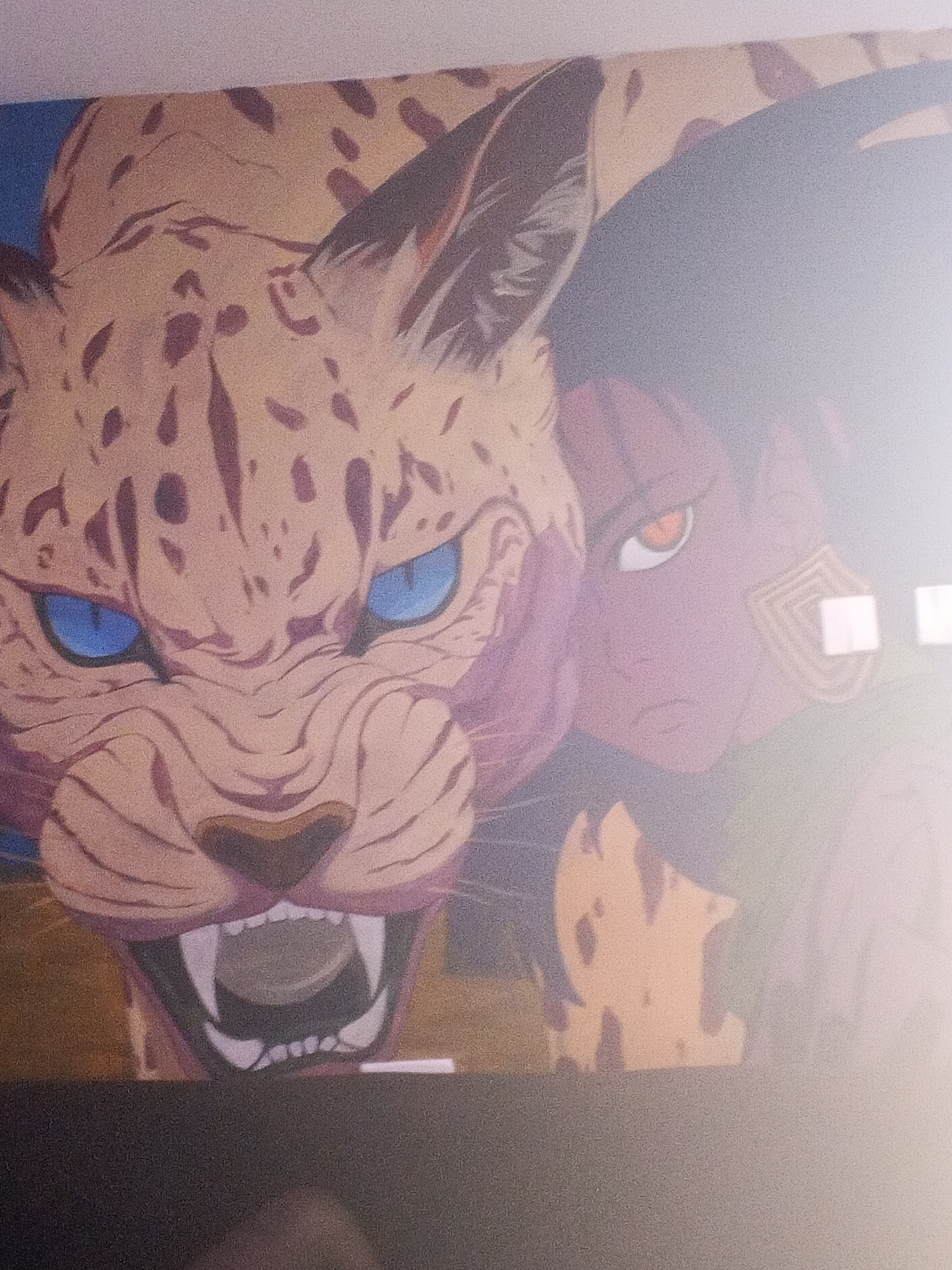 The image displays a stylized illustration, reminiscent of anime or manga, featuring a fierce feline creature and a human-like character.
The dominant subject is a large, spotted feline, likely a leopard or jaguar, positioned in the foreground on the left and center. It has tan fur with dark brown spots, piercing blue eyes, and an open mouth revealing sharp teeth, conveying an aggressive or powerful expression. Its snout is wrinkled, indicating intensity.
Partially visible behind and to the right of the feline is a human-like figure with dark skin and striking red-orange eyes. This character has short, dark hair (partially seen) and a distinctive square-patterned, gold-colored earring or tribal marking on their right ear. Their expression appears serious or determined as they look forward.
The background is simple, with a solid blue hue behind the feline's head and a muted brown/green tone behind the human character. The art style uses bold outlines and flat coloring. The overall scene suggests a powerful bond or a moment of shared intensity between the two subjects.
Notable details include the contrasting blue eyes of the feline against its tan fur, and the unique red-orange eyes and tribal marking of the human figure. The image itself is a photograph of the artwork, showing significant glare and reflections on the right side, which obscure parts of the human character and introduce small white square artifacts. There is no visible text.