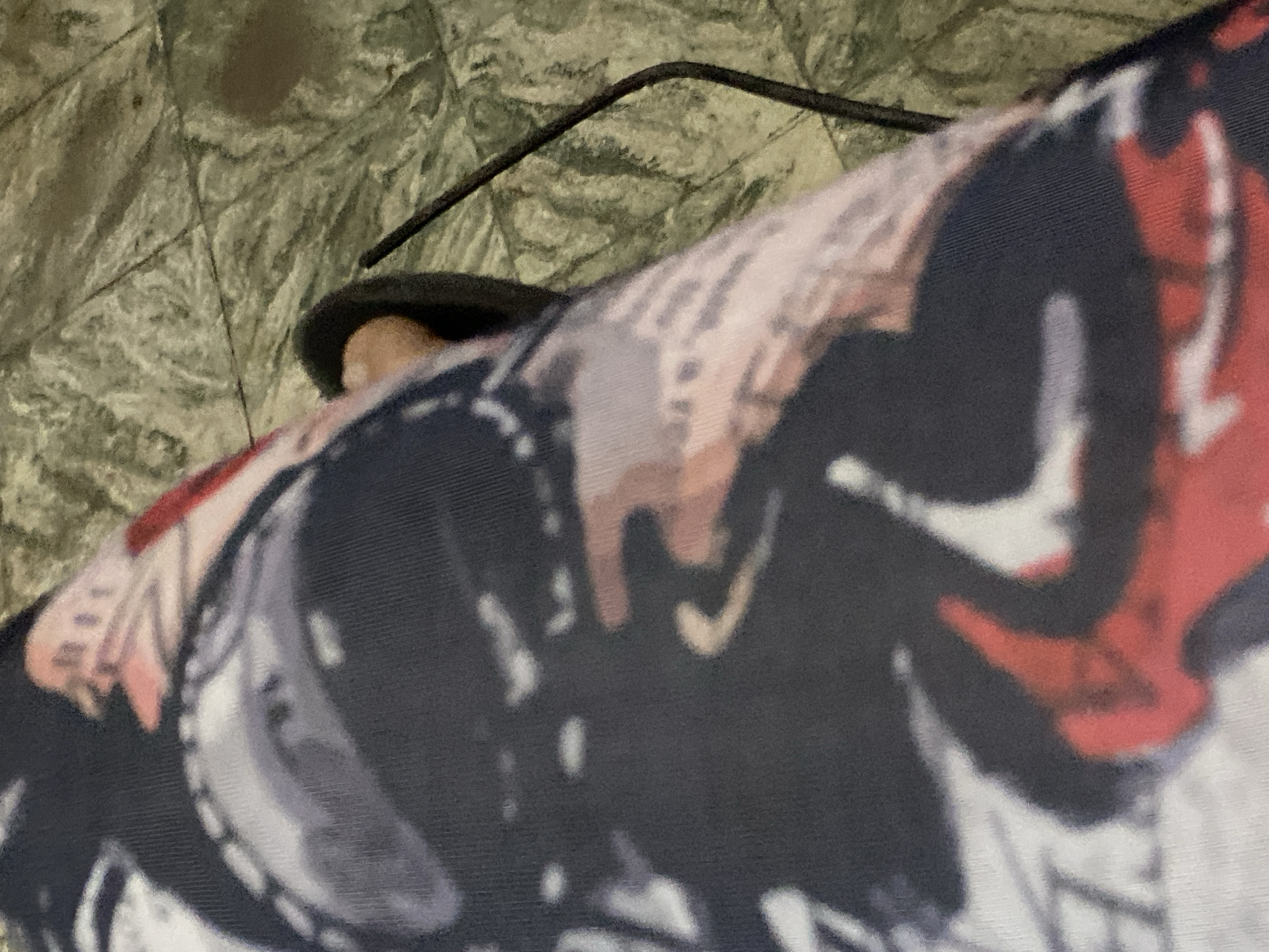The image shows a person wearing a sandal and a patterned garment, possibly a shirt or blanket, against a backdrop of tiled flooring. A thin black wire or cable runs across the top of the sandal. The specific location in Juan Griego, Venezuela, cannot be determined from this image alone.
