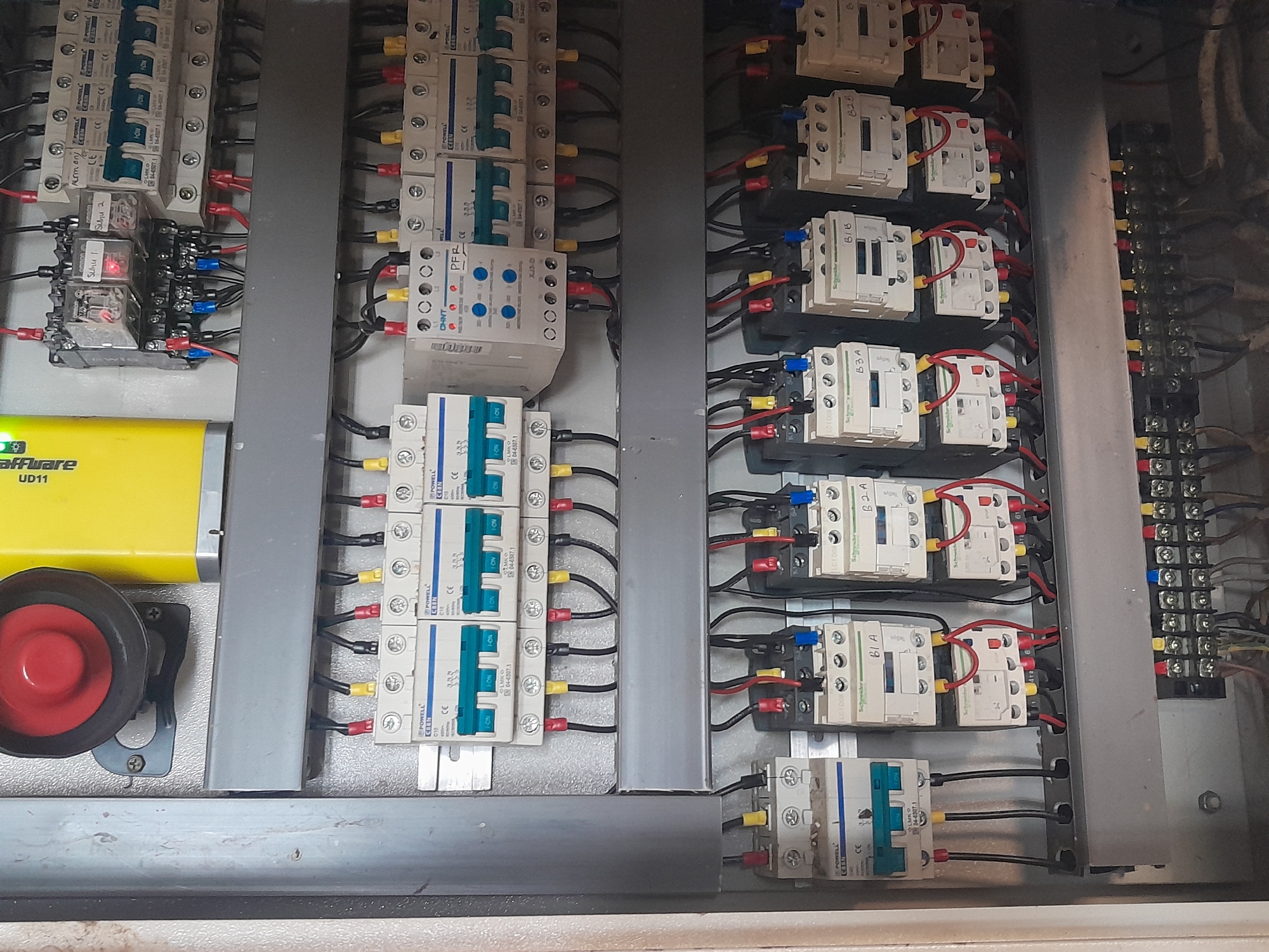 This image is a close-up, eye-level shot of an electrical panel, likely located in Labuhan Ratu Lima, Indonesia. The panel is filled with various electrical components, including circuit breakers, relays, and terminal blocks, all connected by a dense network of colored wires. The components are neatly organized in rows and columns within a metal enclosure. The overall environment appears to be industrial or technical. There are no people or animals visible in the image.