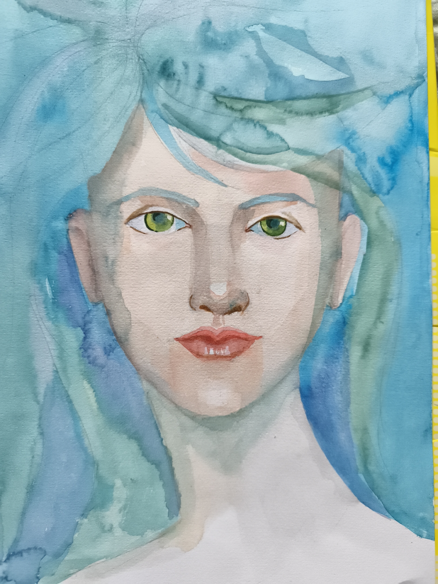 This is a watercolor painting of a portrait of a person with blue hair and green eyes. The person's face is rendered in soft, muted tones, with a hint of pink on the cheeks and lips. The hair is painted in flowing strokes of various shades of blue and green, giving it a wispy, ethereal quality. The background is a wash of light blue and green, further enhancing the dreamlike atmosphere of the artwork. The painting is positioned on a flat surface, with the right edge of the artwork adjacent to a yellow ruler. The specific location in the city of Saint-Denis, France, is not discernible from the provided image.