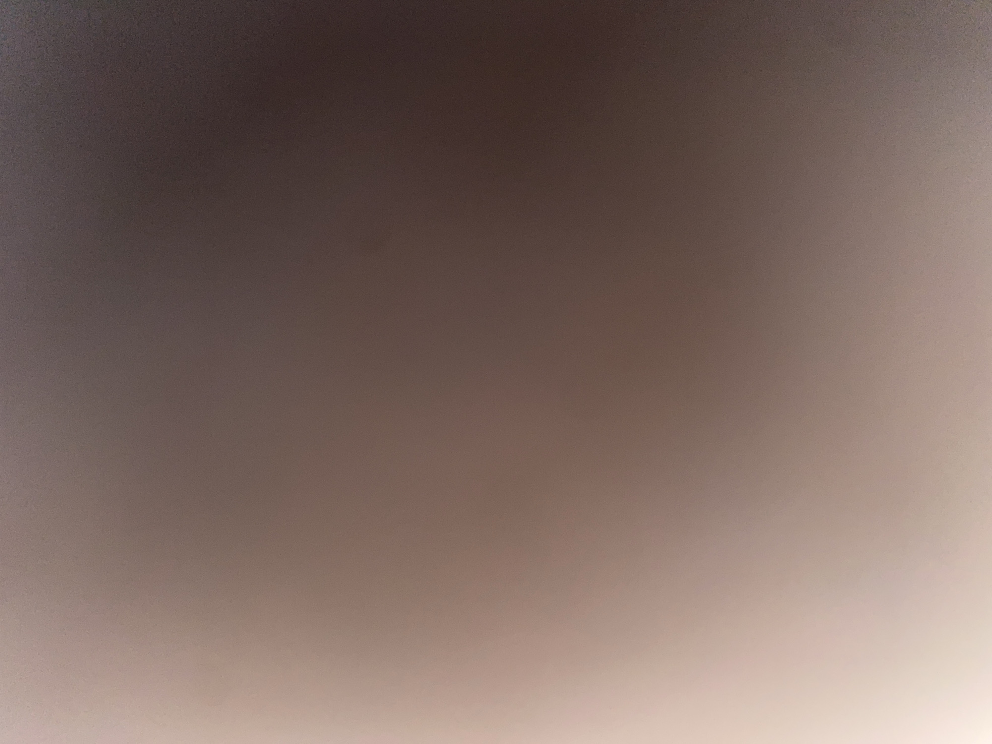 The image provided is an abstract, out-of-focus shot of a textured surface. It displays a gradient of colors ranging from a light, almost white tone on the left to darker, brownish-grey tones on the right. The texture appears to be grainy or possibly like fabric with a subtle pattern. No discernible objects, people, or environmental features are visible, making it impossible to determine its location in Ablanitsa, Bulgaria, or any specific context.