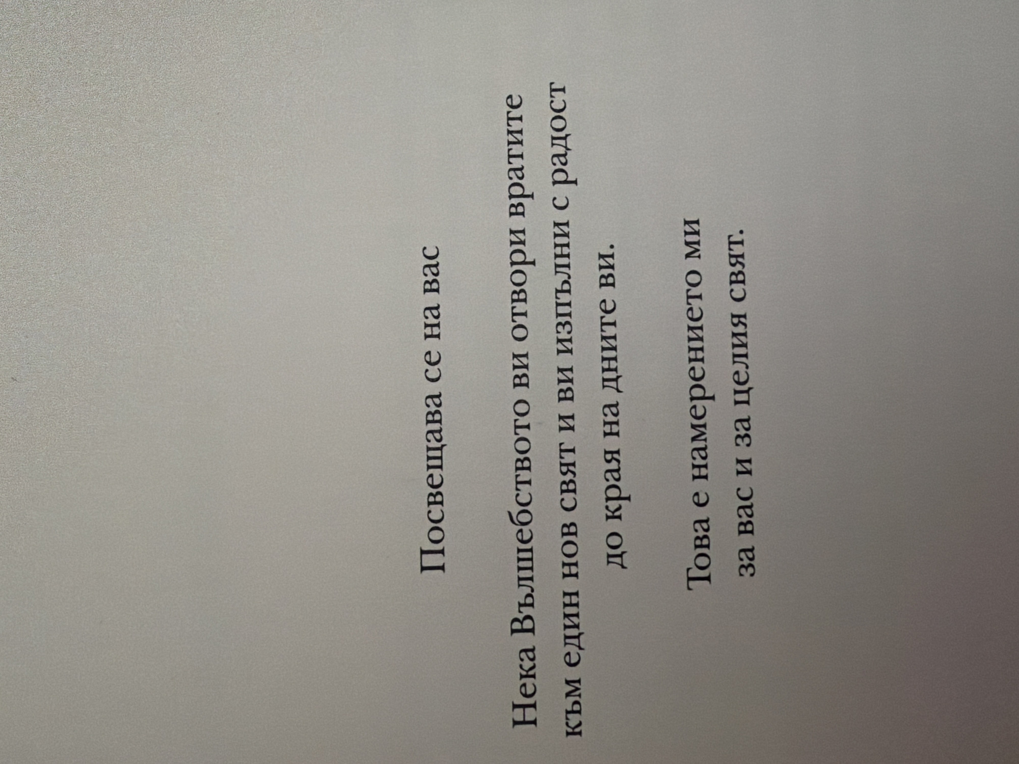 The image displays text printed on a textured, light gray background. The text is in Bulgarian and appears to be a quote or a message. The first line reads "Посвещава се на вас" (Dedicated to you). The second, third, and fourth lines read "Нека Вълшебството ви отвори вратите към един нов свят и ви изпълни с радост до края на дните ви." (May Magic open the doors to a new world for you and fill you with joy until the end of your days.). The final two lines read "Това е намерението ми за вас и за целия свят." (This is my intention for you and for the whole world.). There are no people, specific objects, or discernible environmental features beyond the textured surface the text is printed on. The image is a close-up of the text, with no indication of its location in Pazardzhik, Bulgaria, or any other geographical context.