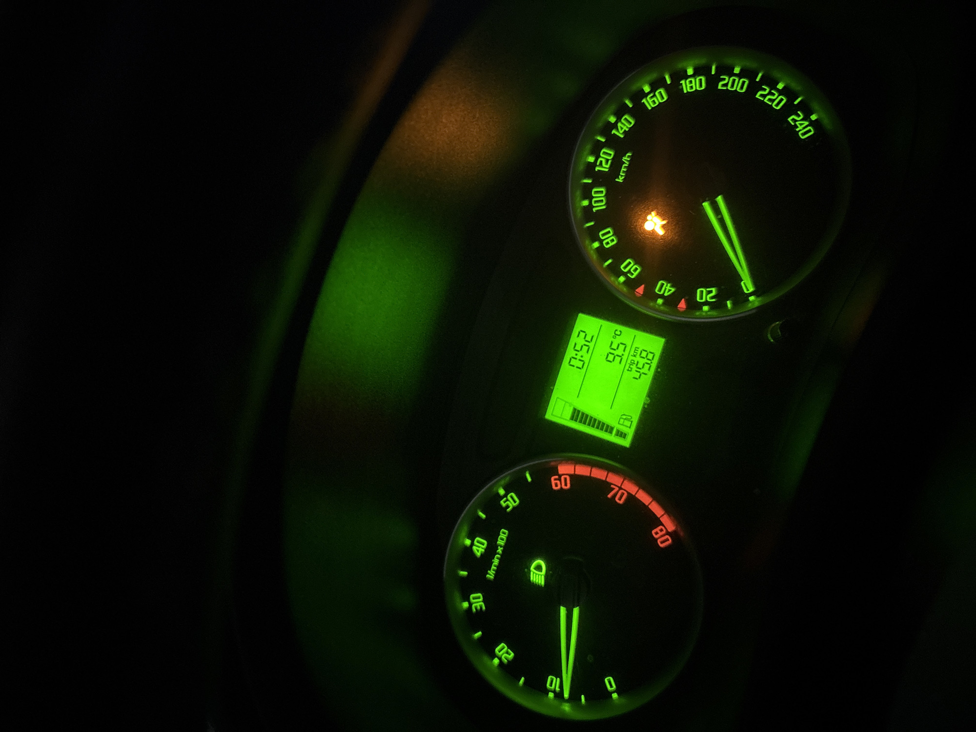 The image depicts a car dashboard at night, illuminated by green and red lights. The speedometer indicates a speed near 0 km/h, and the tachometer suggests the engine is idling. A digital display shows the time as 0:52, a temperature of 9.5 degrees Celsius, and a trip distance of 45.8 km. The location is unknown, with no indicators of Plovdiv, Bulgaria. The airbag indicator is lit.