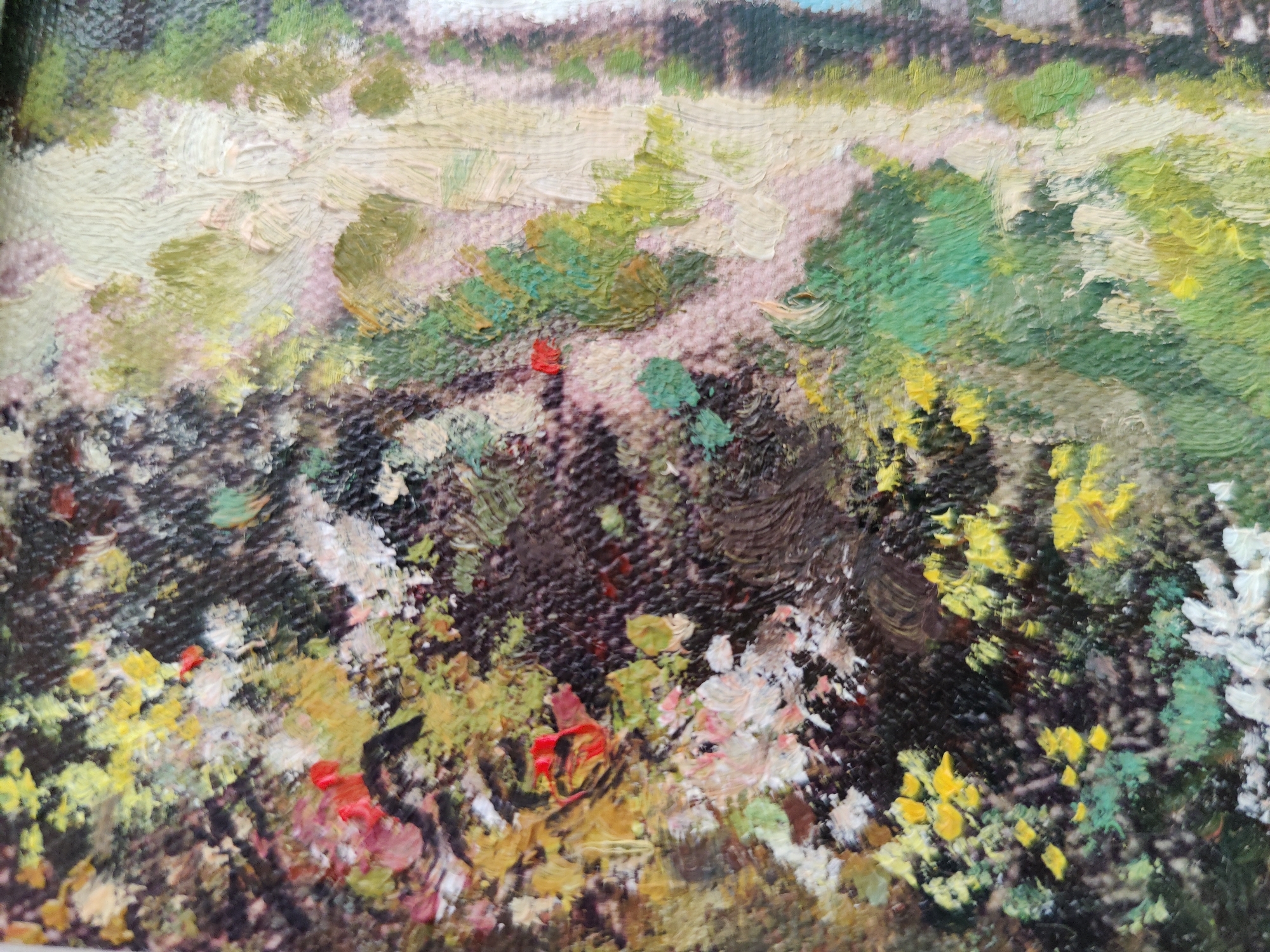 The image is a close-up, textured oil painting of a dense, vibrant natural scene, likely a garden or meadow. The foreground is dominated by a thick layer of foliage in various shades of green, brown, and black, interspersed with bright yellow and white flowers, and pops of red. The brushstrokes are thick and impasto, giving the painting a tactile quality. In the mid-ground, patches of lighter, sandy-colored earth or gravel are visible, also textured with thick paint. Further back, the painting depicts a blurred landscape with hints of trees or structures against a pale sky. There are no people or discernible actions depicted in the artwork. The painting does not provide any specific visual cues to identify a location within the city of Rybnitsa, Moldova.
