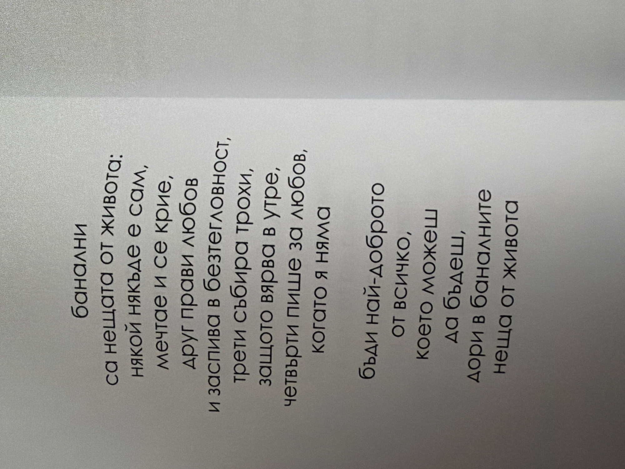 The image displays a section of text printed on a light gray, textured surface, likely paper. The text is in Bulgarian and appears to be a poem or prose, presented in a serif font. The text is centered on the visible portion of the page. There are no people, objects, or any environmental elements present in the image besides the printed text and the surface it is on. The location of this image within the city of Pazardzhik, Bulgaria, cannot be determined from the visual information provided.