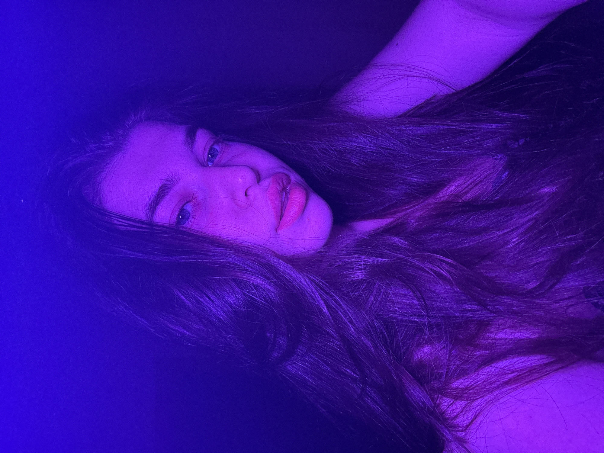 The image shows a woman with long, dark hair, under a strong purple light. Her face is visible, and she appears to be lying down. There is no evidence to suggest the image was taken in Мещёры, Russia or to determine its location.